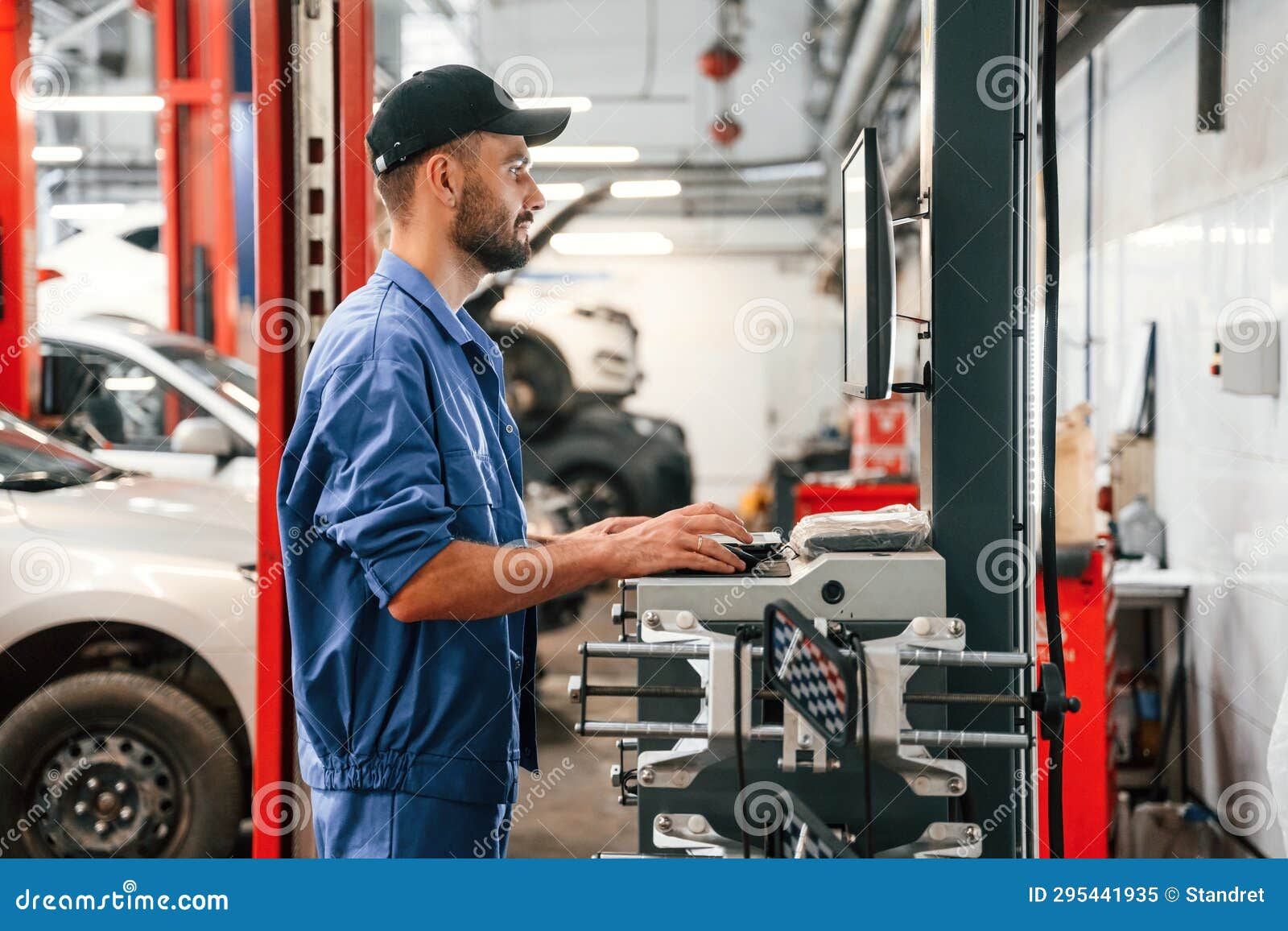 Standing by Computer Terminal. Auto Mechanic Working in Garage Stock