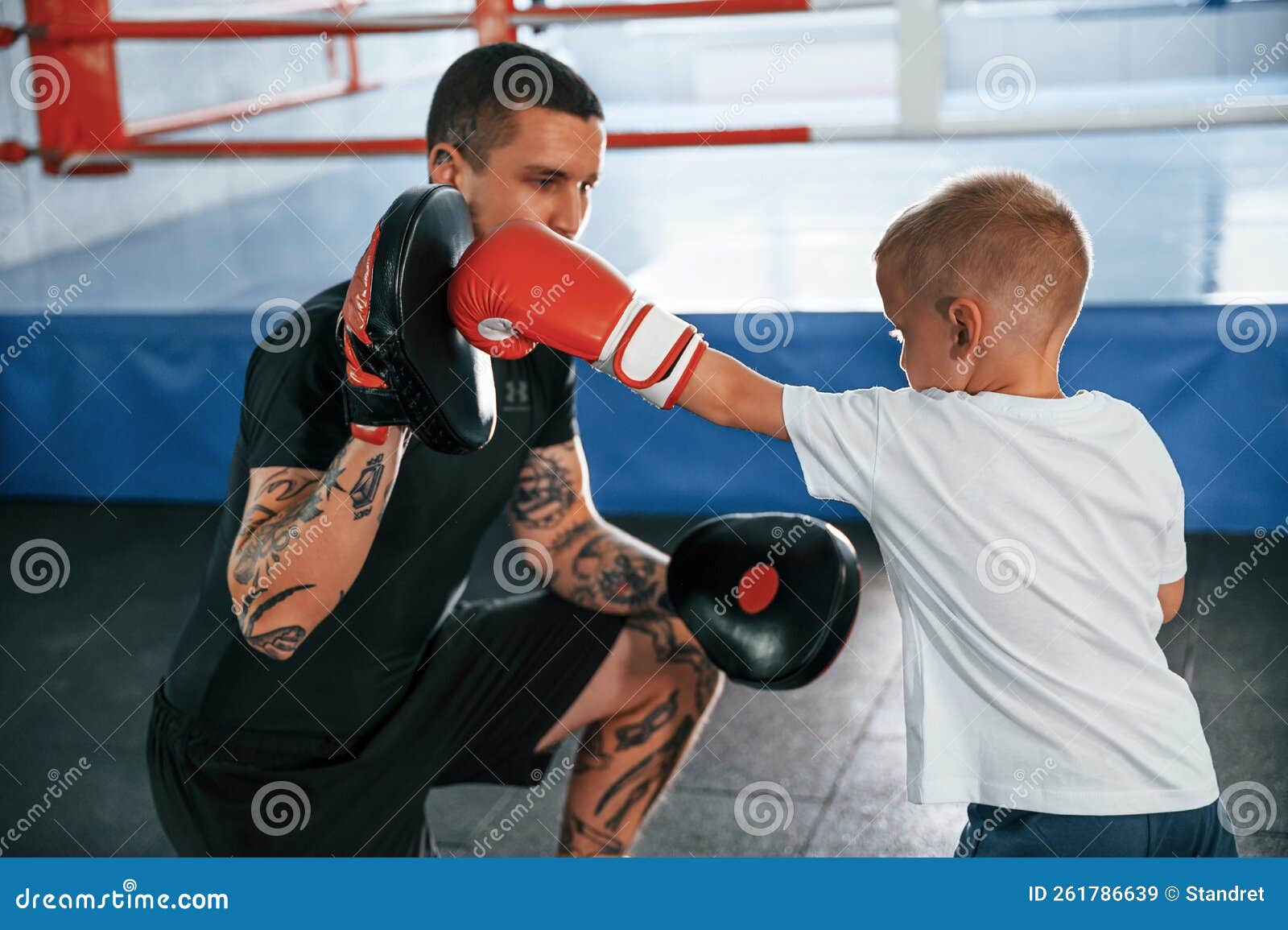 Standing and Practicing the Punches. Coach is Teaching the Boy Box