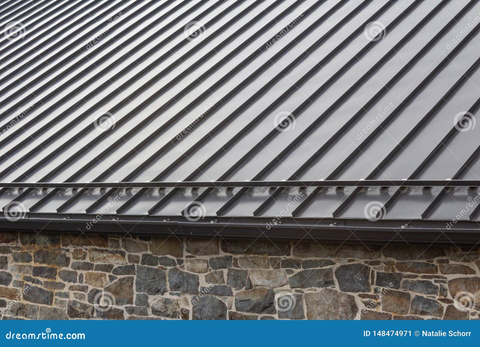 standing seam modern metal roof over vintage stone wall