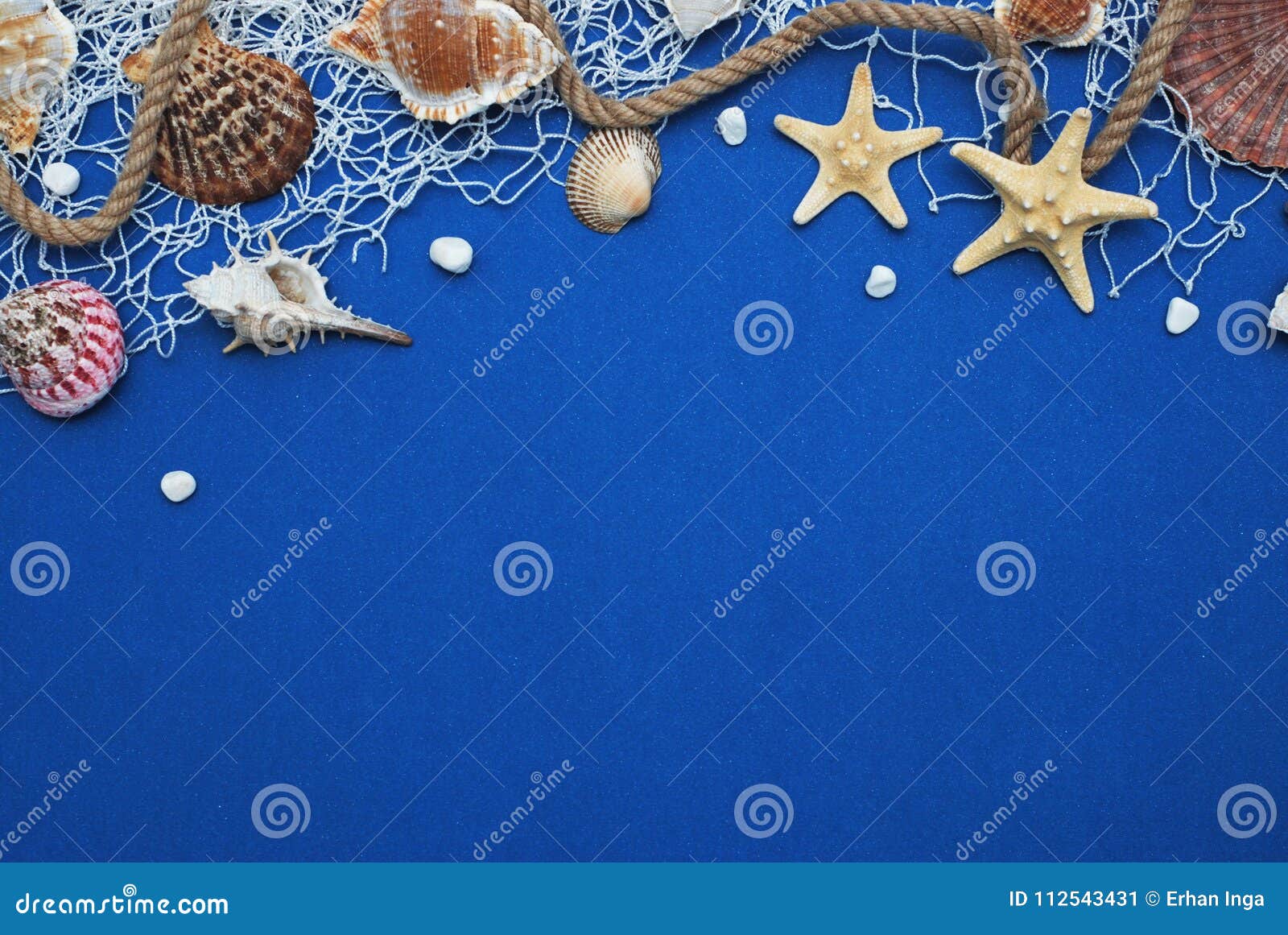 starfish, shell, stones, rope and net against a blue background with copy space. summer holliday. nautical, marrine concept.