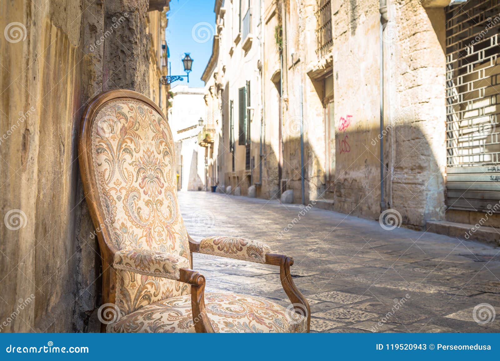 Stary krzesło w tradycyjnej ulicie Lecka, Włochy. Lecka miasteczko, Włochy Rocznika krzesło z starą grodzką ulicą w tle