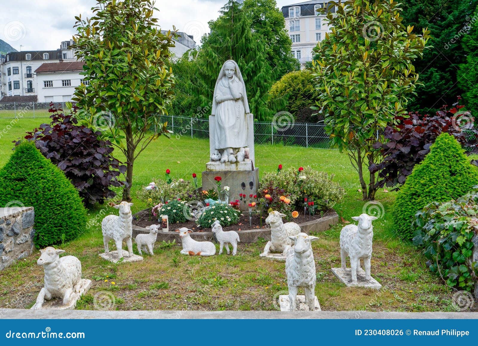 Statue Of Bernadette Praying To Our Lady Of Lourdes With Flowers Next