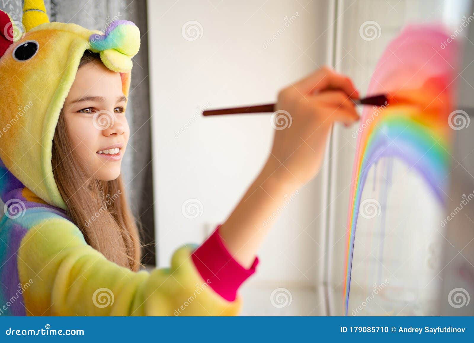 teen girl in kigurumi draws rainbow on window home