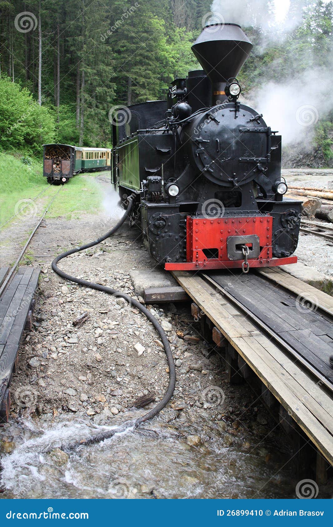 Steam train refilling with water. A steam train has stopped on a bridge to refill its boiler with from a river.