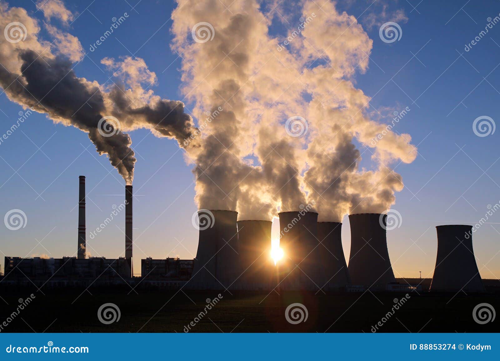 steaming cooling towers of coal power plant against the sun