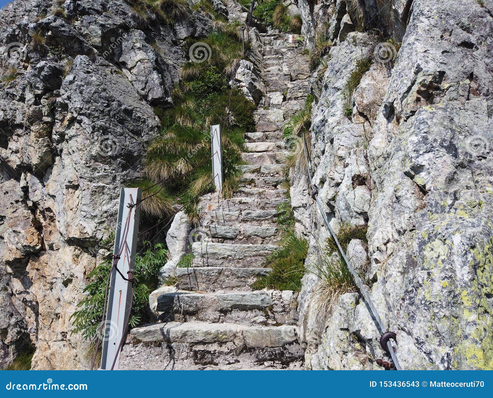 steep stairway carved out of stone on a mountain path. steel cables on its sides. orobie. italian alps