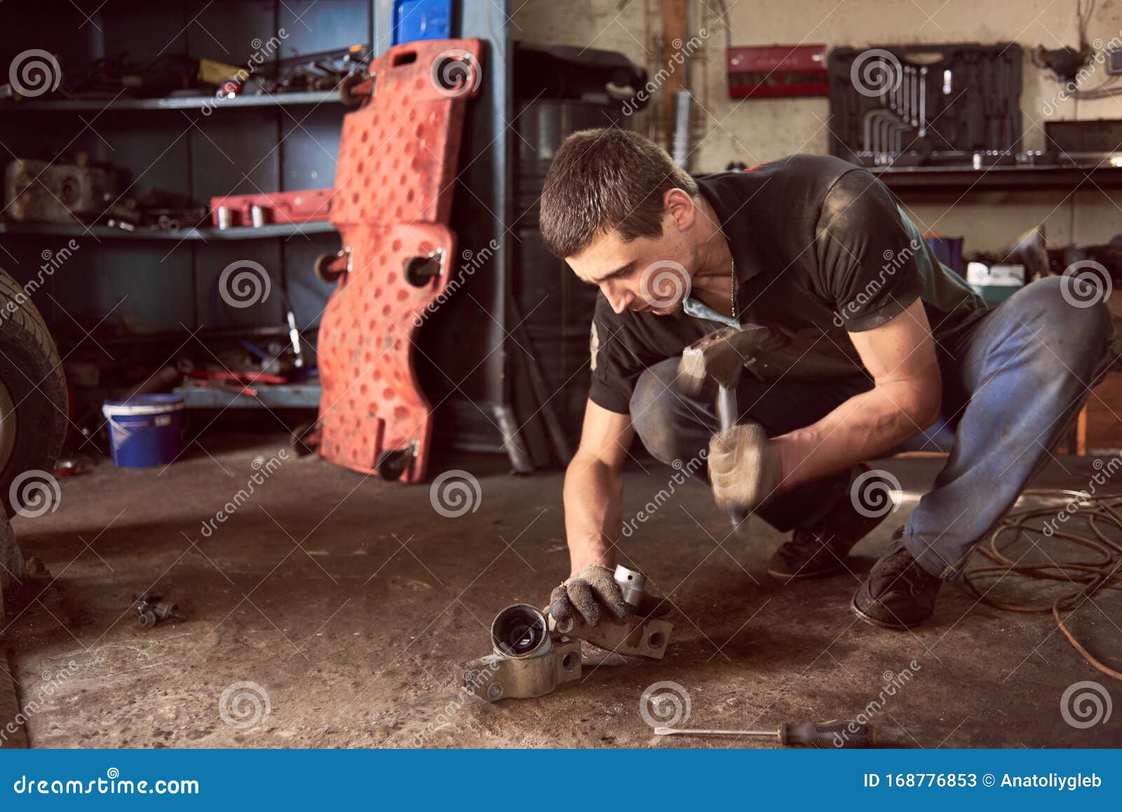 Sterke Automechanica in Vuile Werkkleding, Die Op De Werkt Aan Details Van Auto's, Met Hamer Die Helpt Bij De Stock Afbeelding - Image of mannetje, handhaaf: 168776853