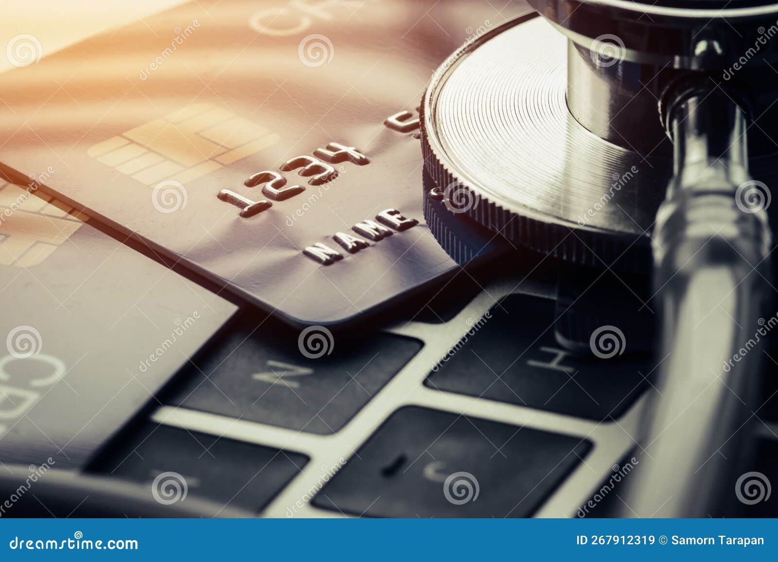stethoscope on mock up credit card with number on card at computer in hostpital desk. health insurance and cost of medical care,