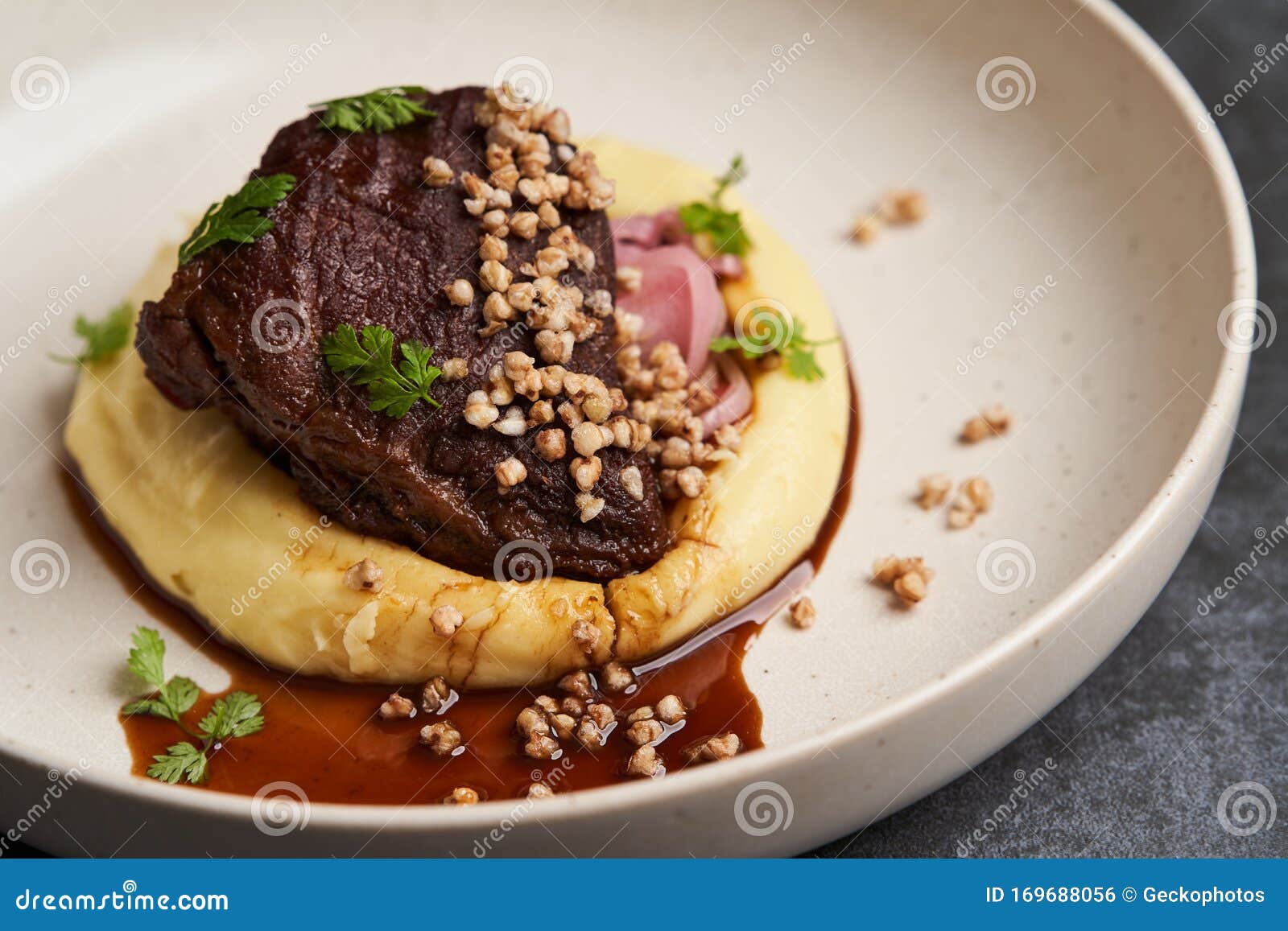 Stewed Veal Cheeks with Mashed Potatoes on a White Plate, Closeup