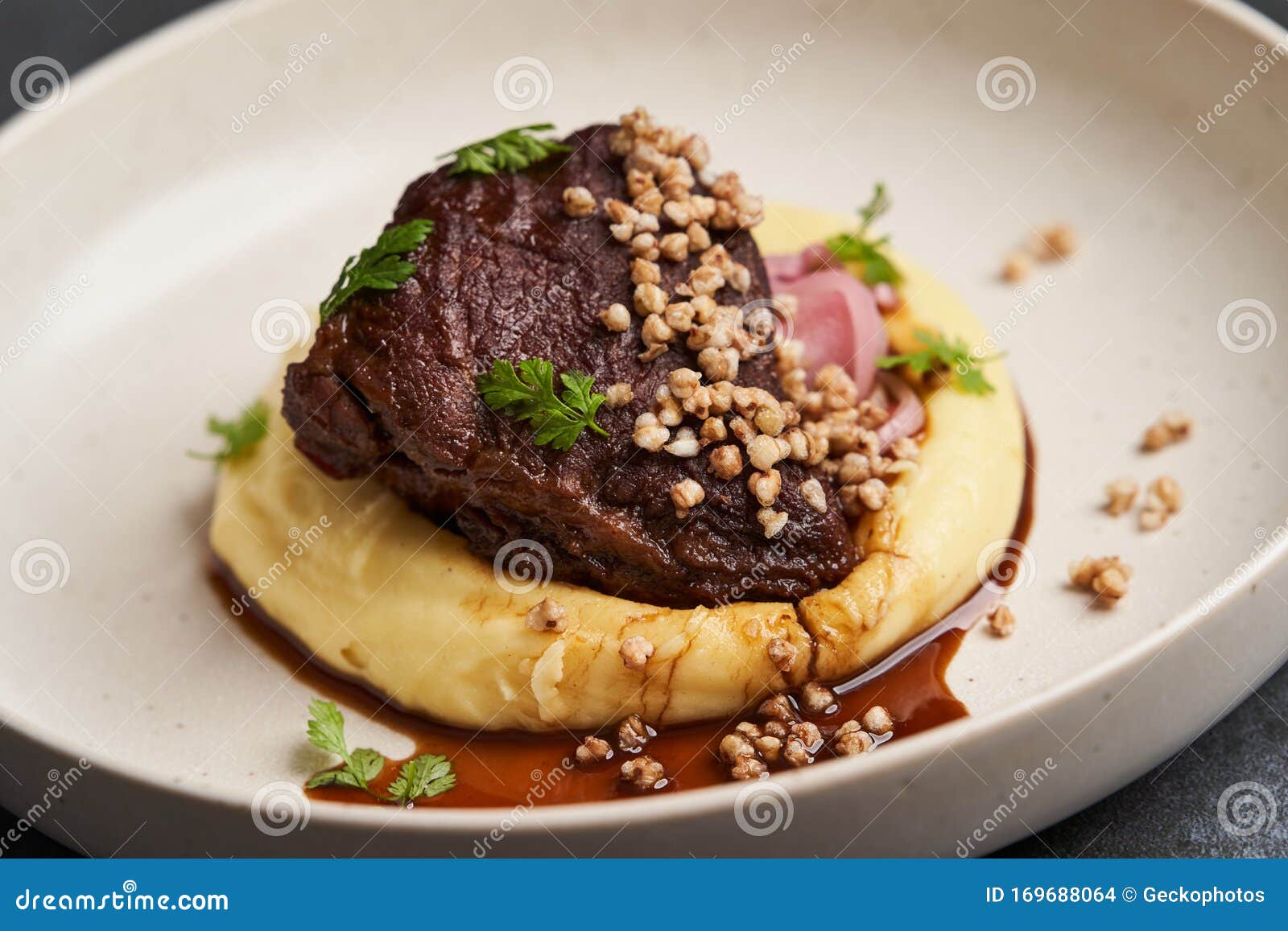 Stewed Veal Cheeks with Mashed Potatoes on a White Plate, Closeup