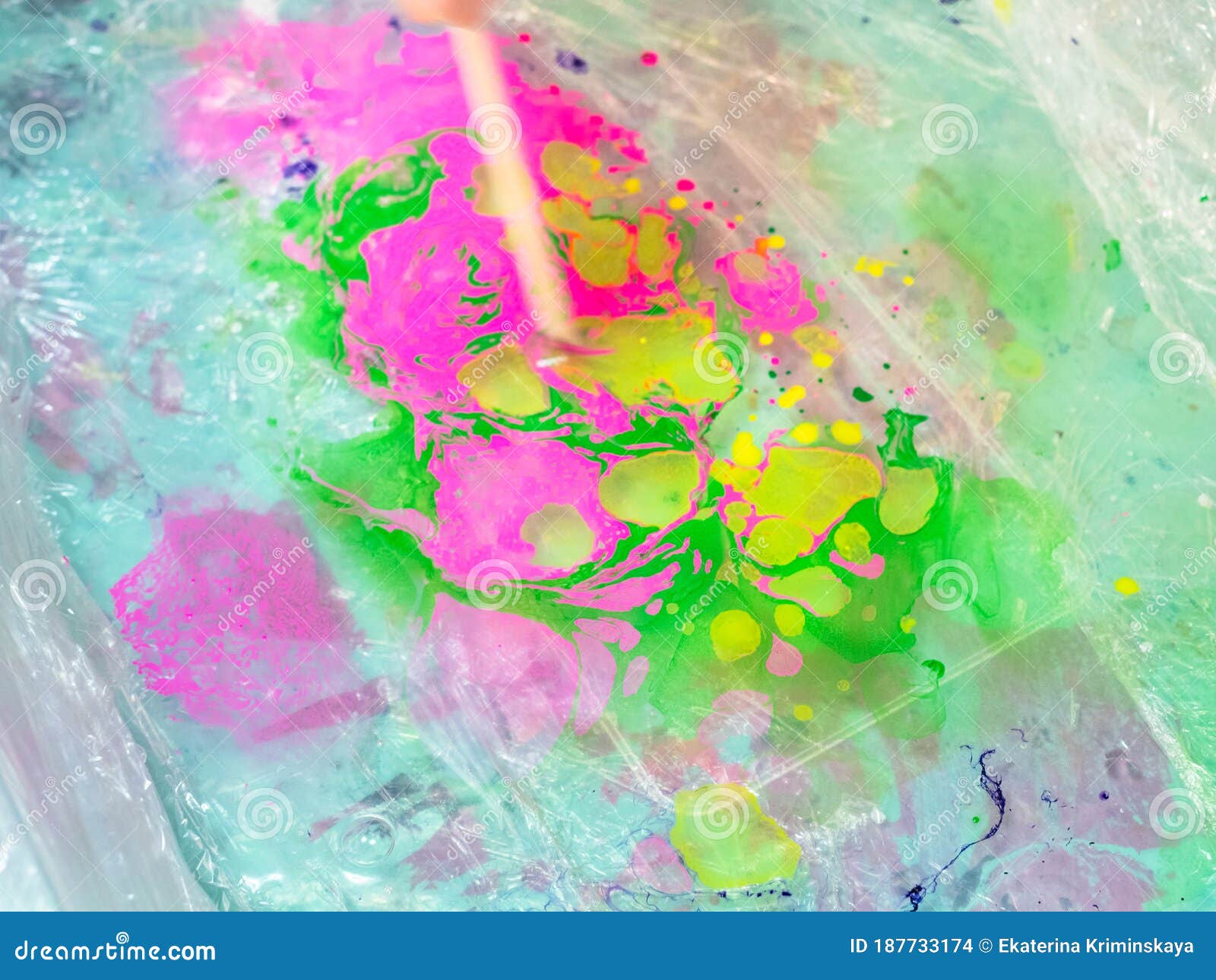 stick mixes paints on surface of liquid in basin