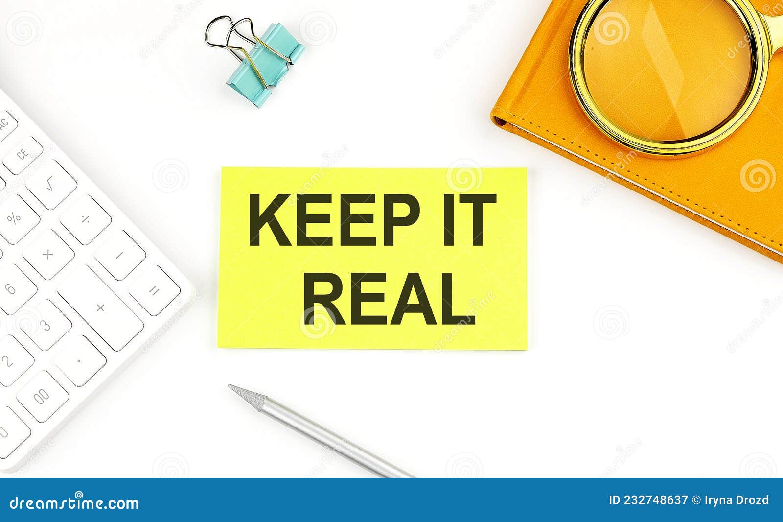 sticker with the text keep it real on white background, near calculator and notebook