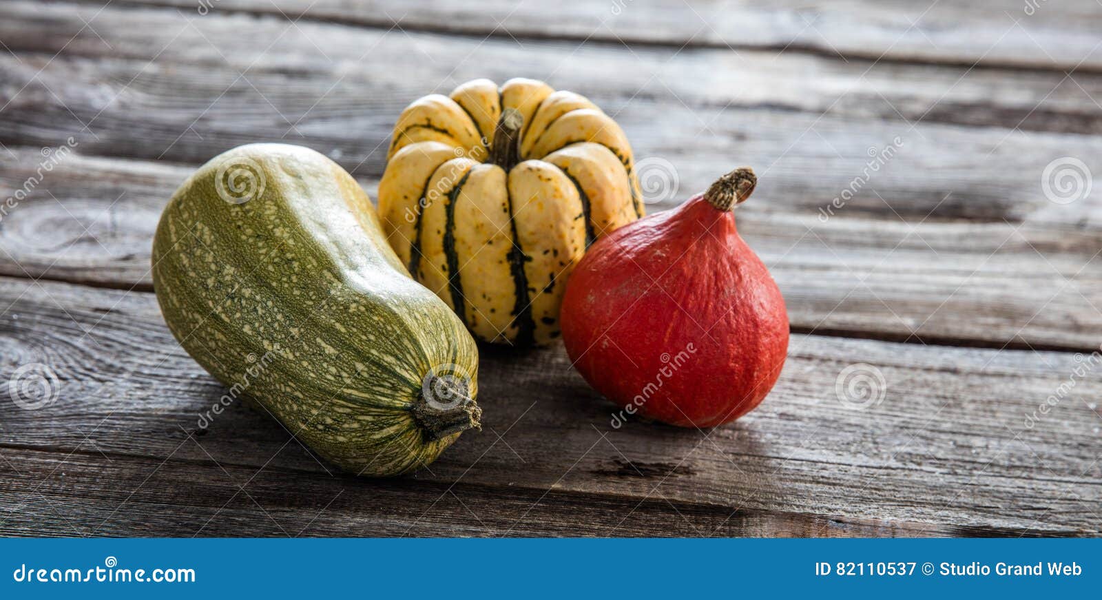 still life of kuri squash and green gourd over wood