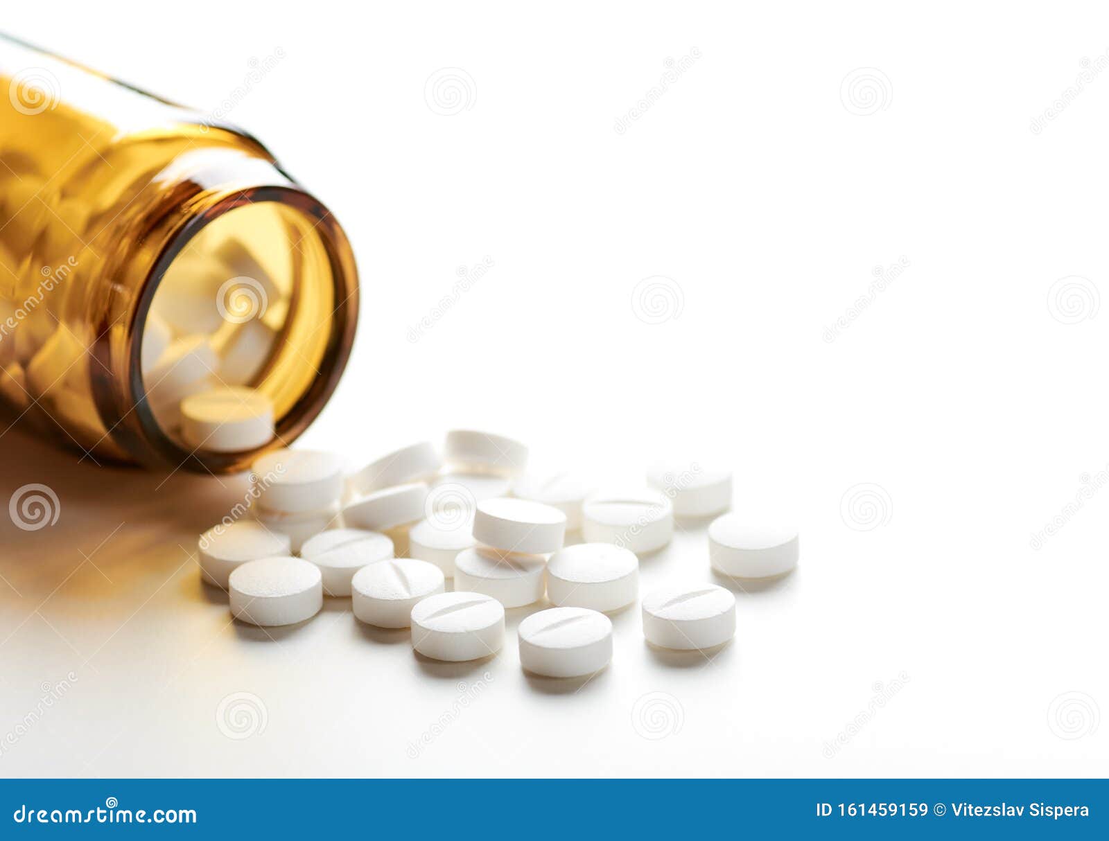 still life with pile of white pills or tablets and glass bottle or glass