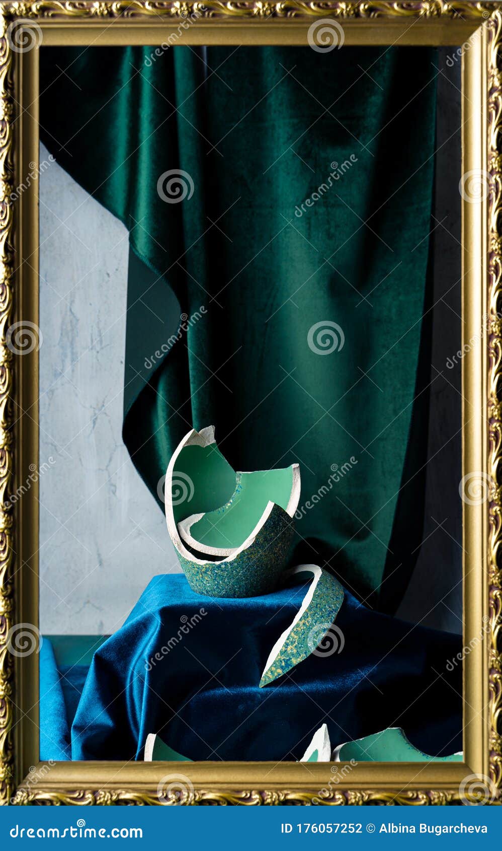 stilllife with remnants of broken teal colored vase, emerald green and dark blue velvet, and picture frame
