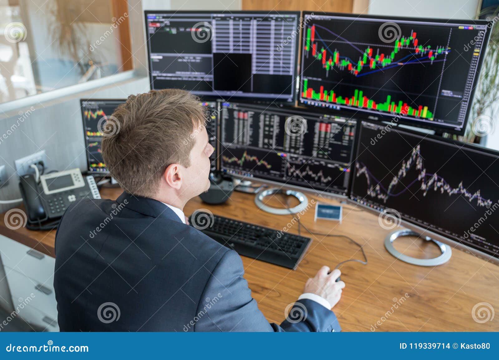 Stock Trader Looking At Computer Screens In Trdading Office Stock