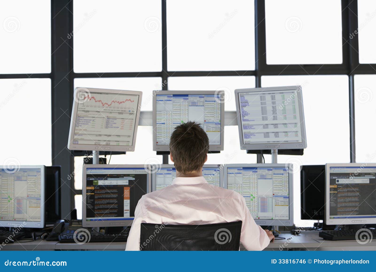 stock trader looking at multiple computer screens