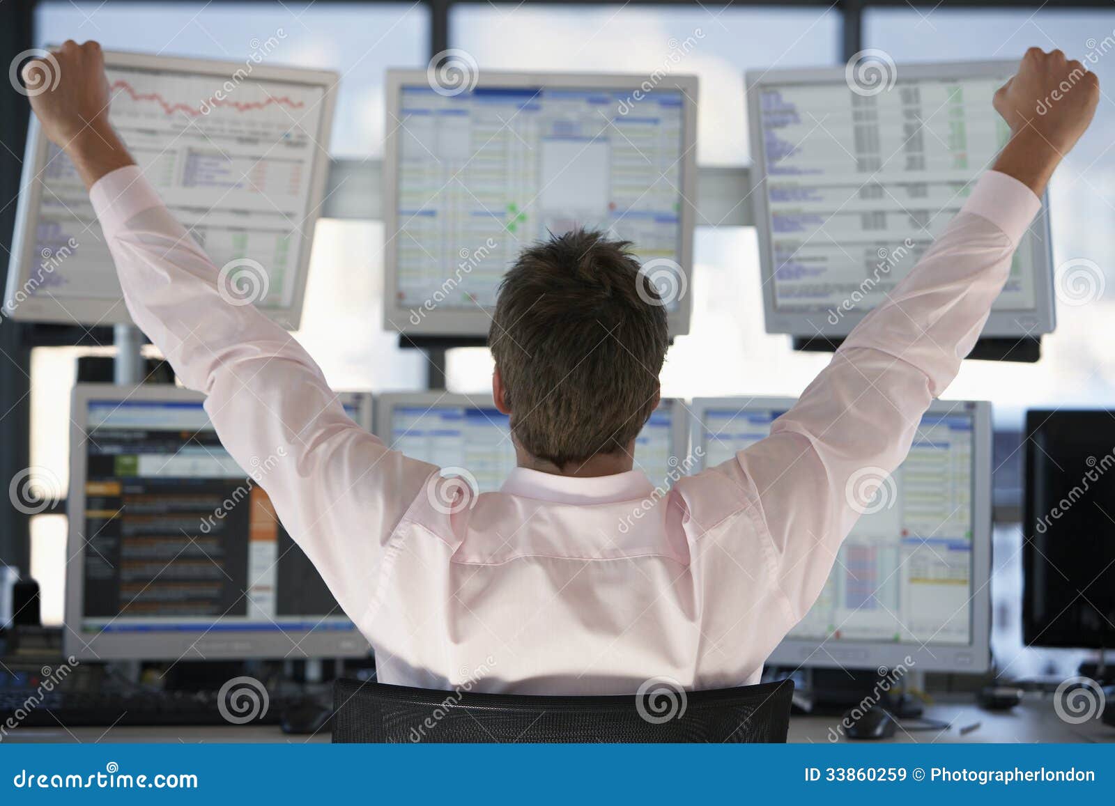 stock trader watching computer screens with hands raised