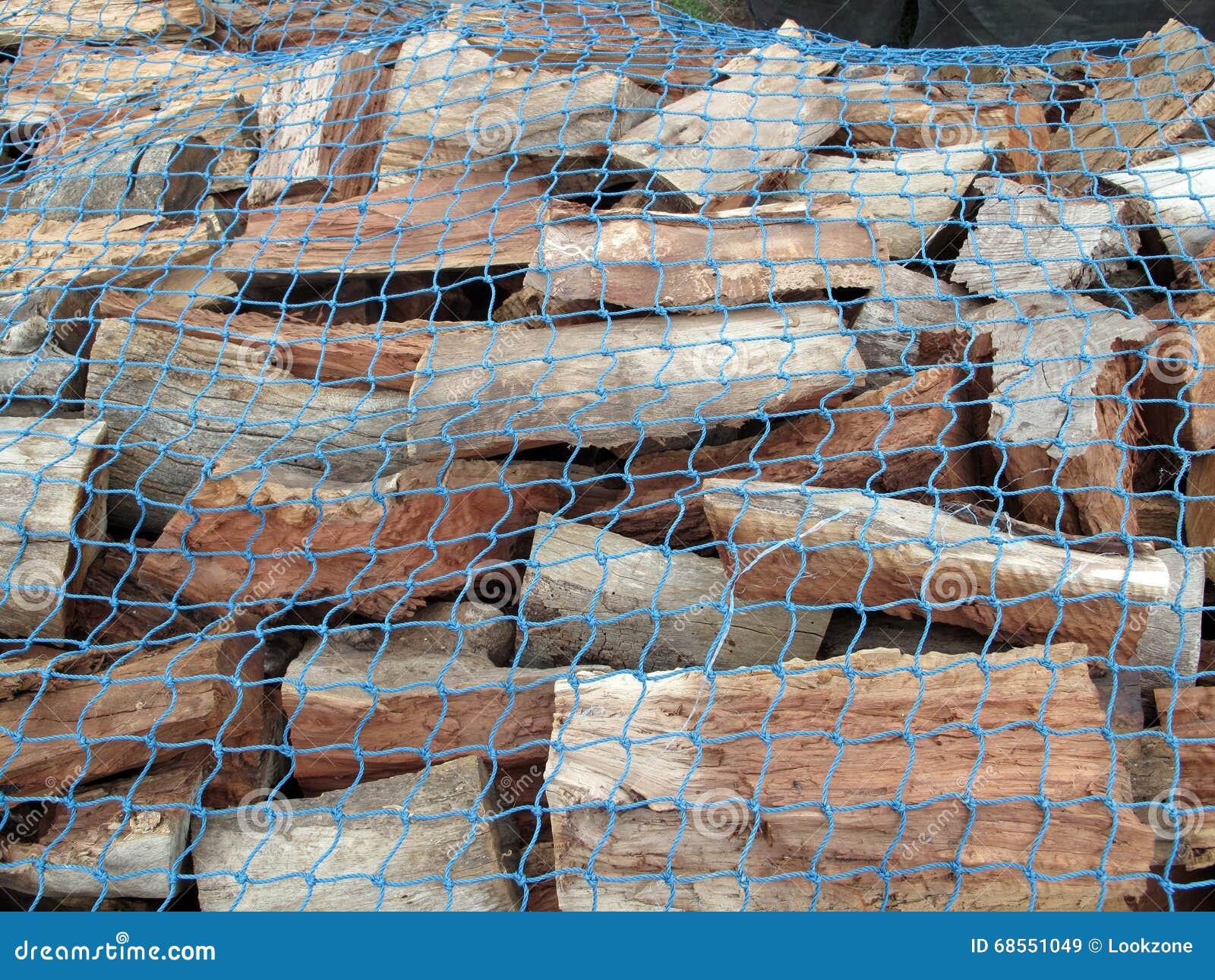 A Stockpile of Fresh Cut Firewood. A pile of fresh cut firewood covered with blue netting used for safe transportation. Photo taken in Adelaide, Australia.