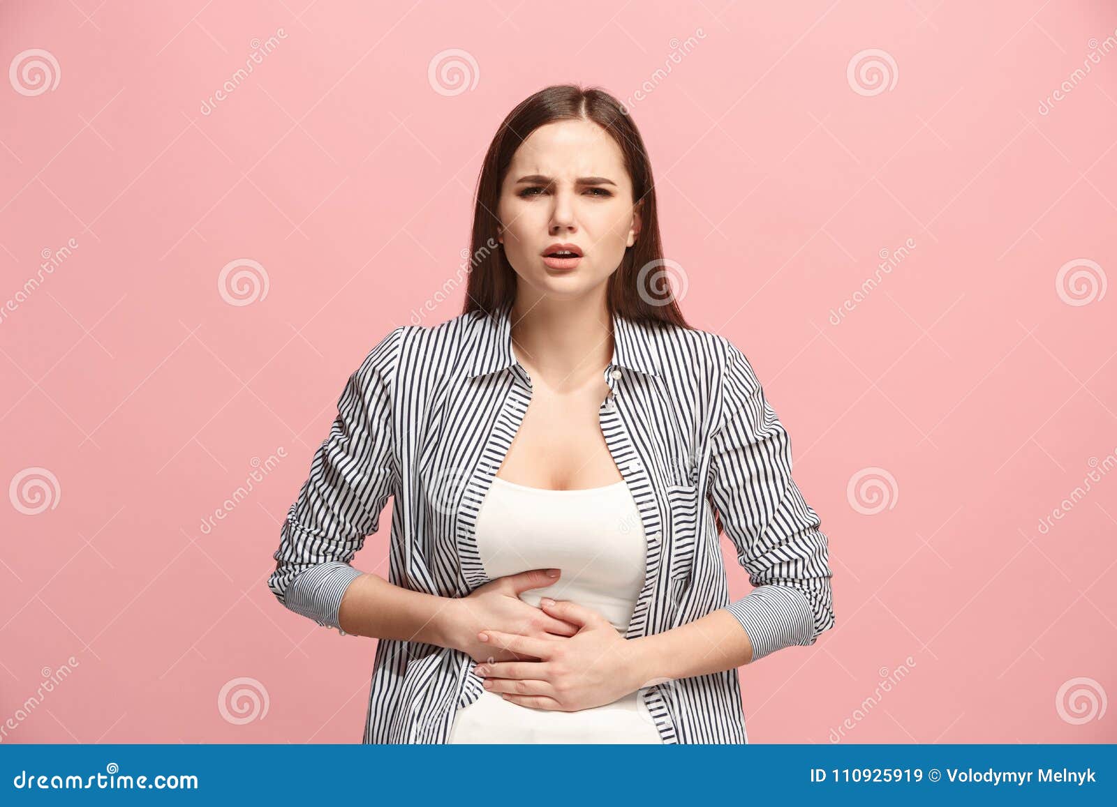 the stomach ache. the sad woman with stomach ache or pain on a pink studio background.