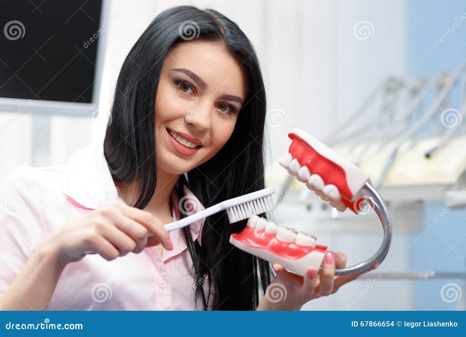 Stomatology and health care concept. Beautiful young woman explains to dentures how to properly care for your teeth