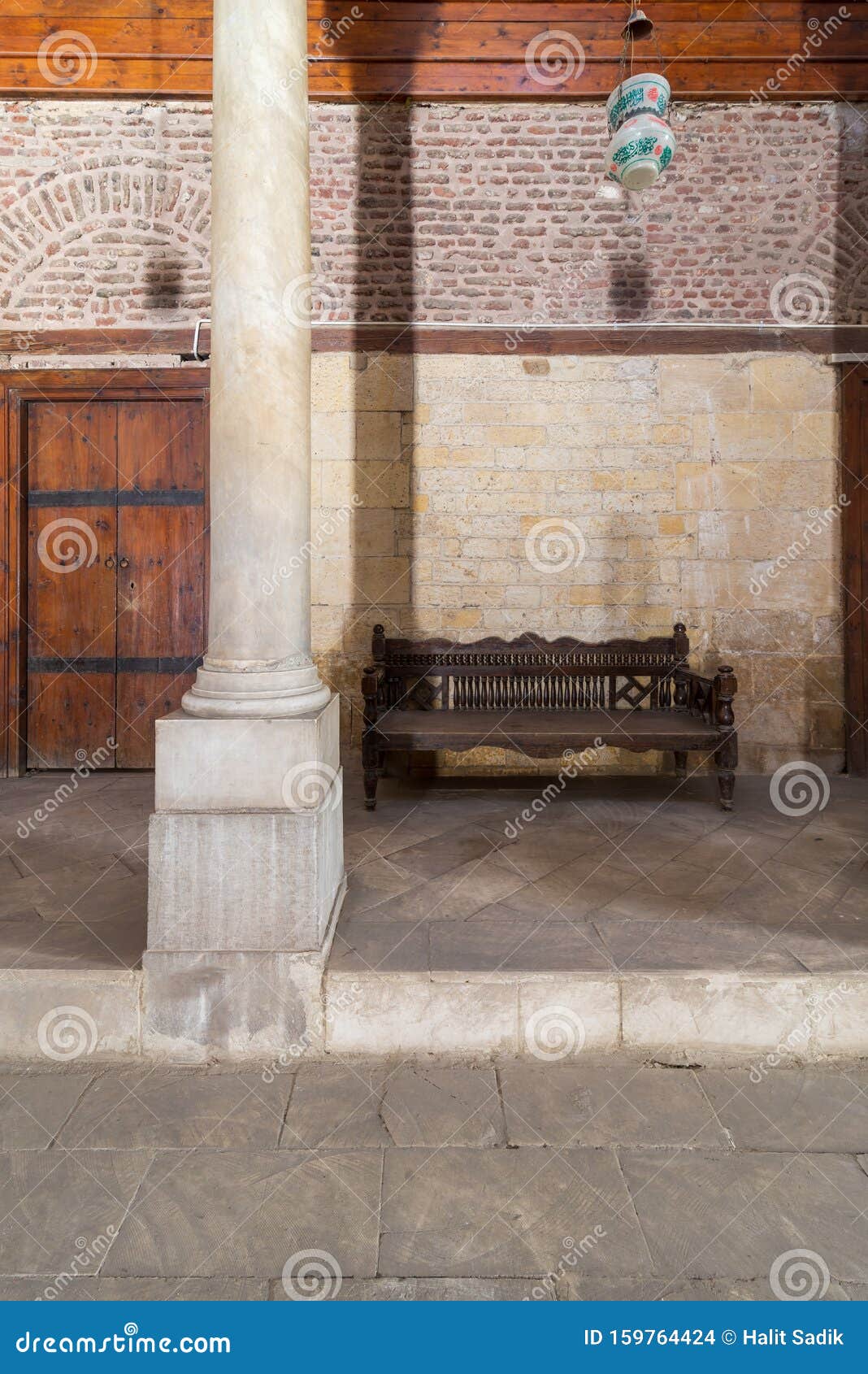 stone bricks wall and aged wooden couch at main hall of historic mamluk era beshtak palace, cairo