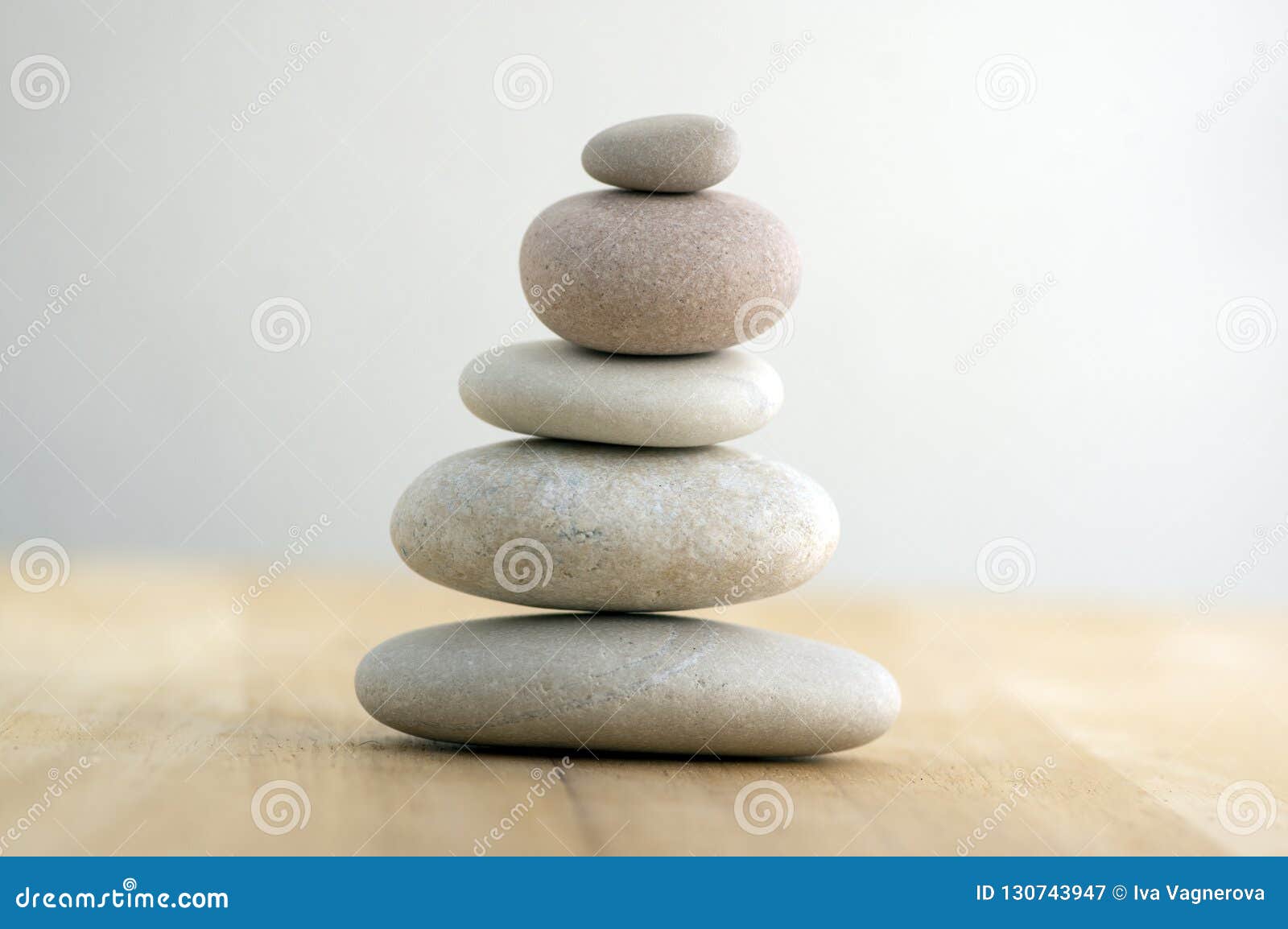 stone cairn on striped grey white background, five stones tower, simple poise stones, simplicity harmony and balance, rock zen