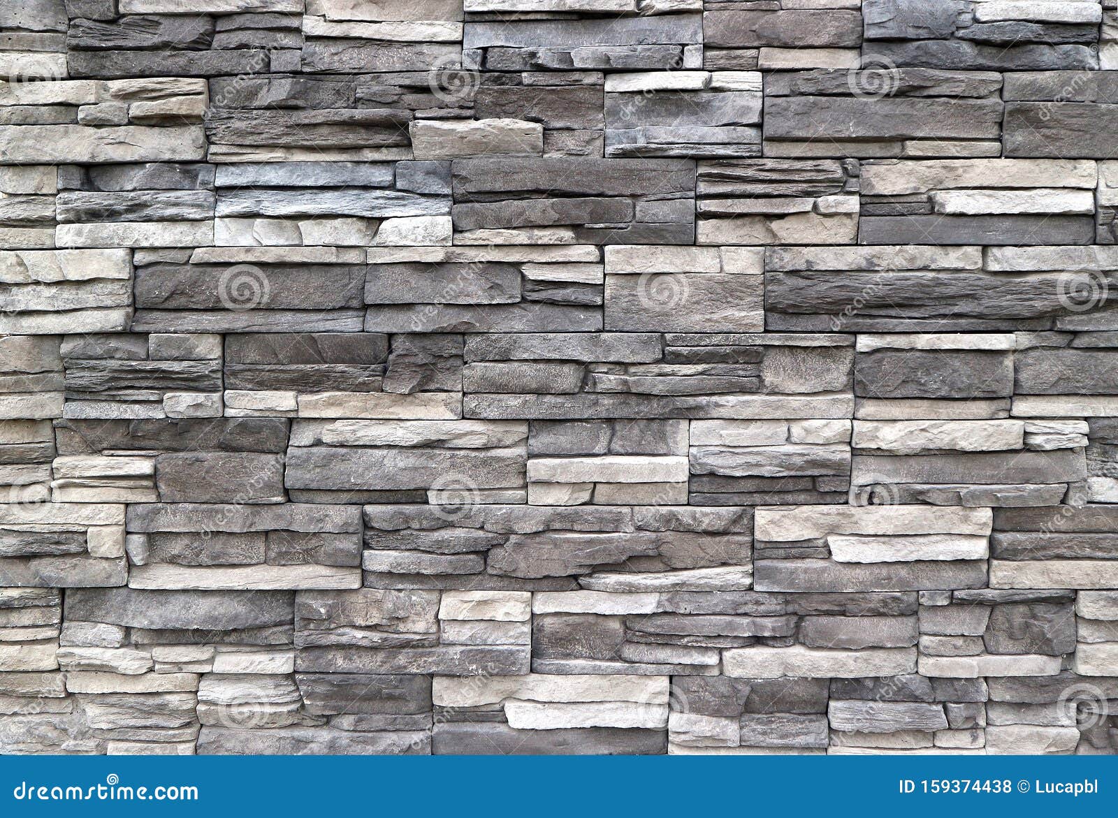 stone cladding wall made of  striped stacked slabs of natural rocks. colors are dark gray and white