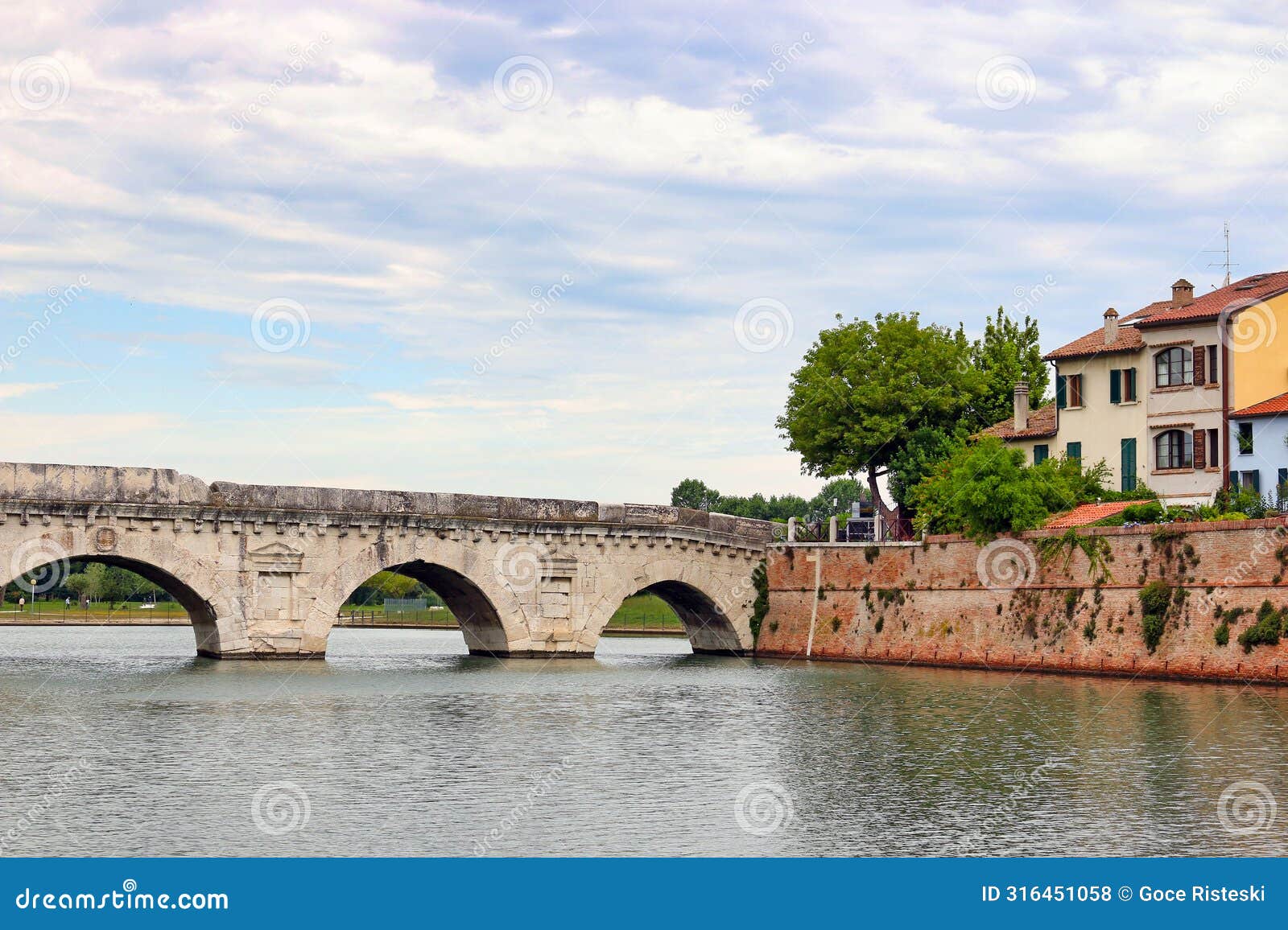 stone tiberius bridge and old town buildings cityscape in rimini