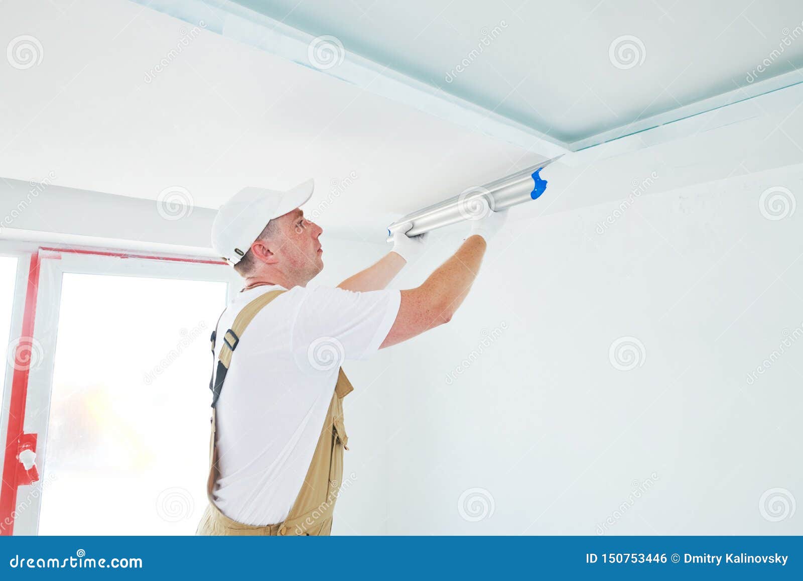 Painter With Putty Knife Plasterer Smoothing Ceiling Surface At