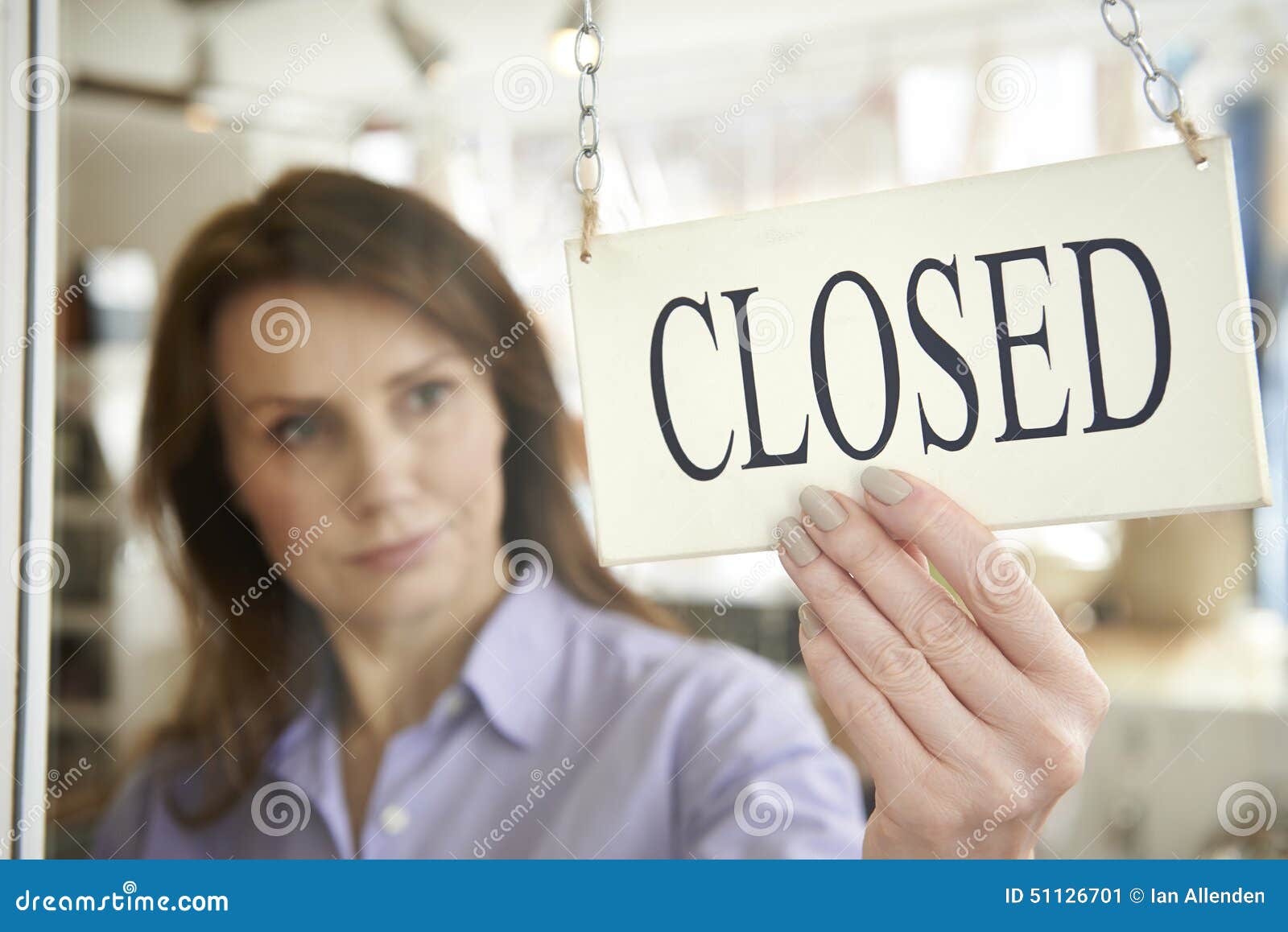 store owner turning closed sign in shop doorway