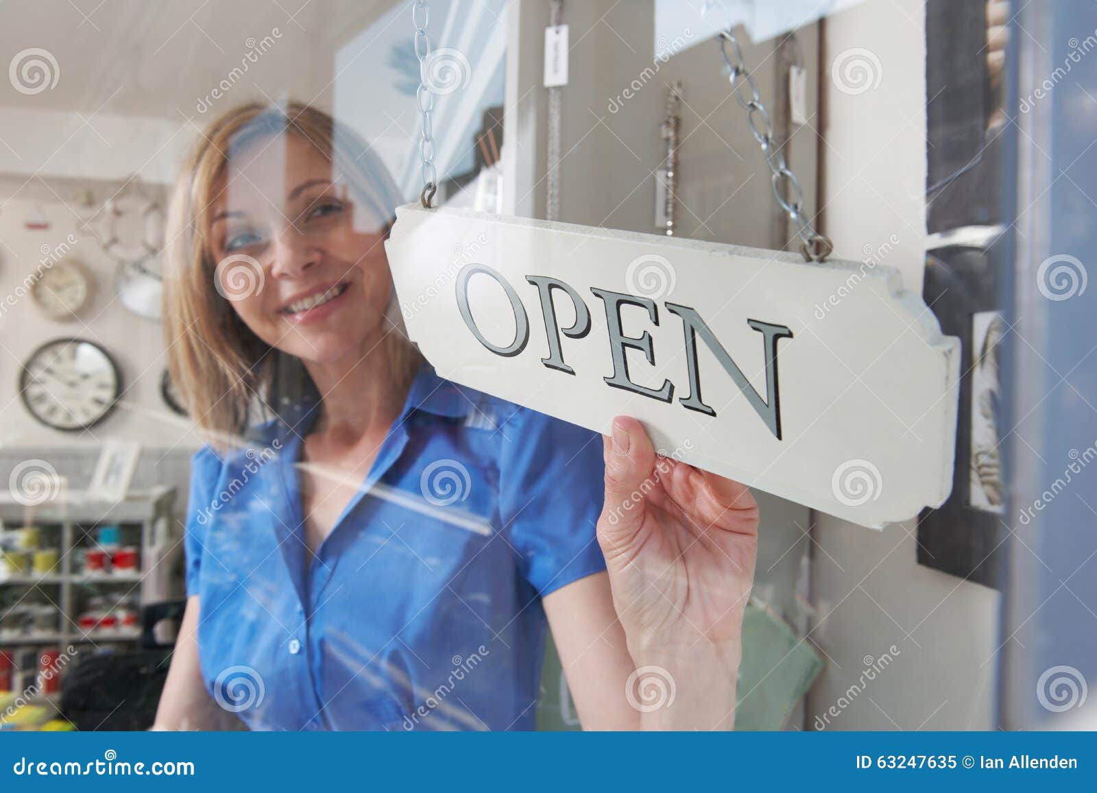 store owner turning open sign in shop doorway