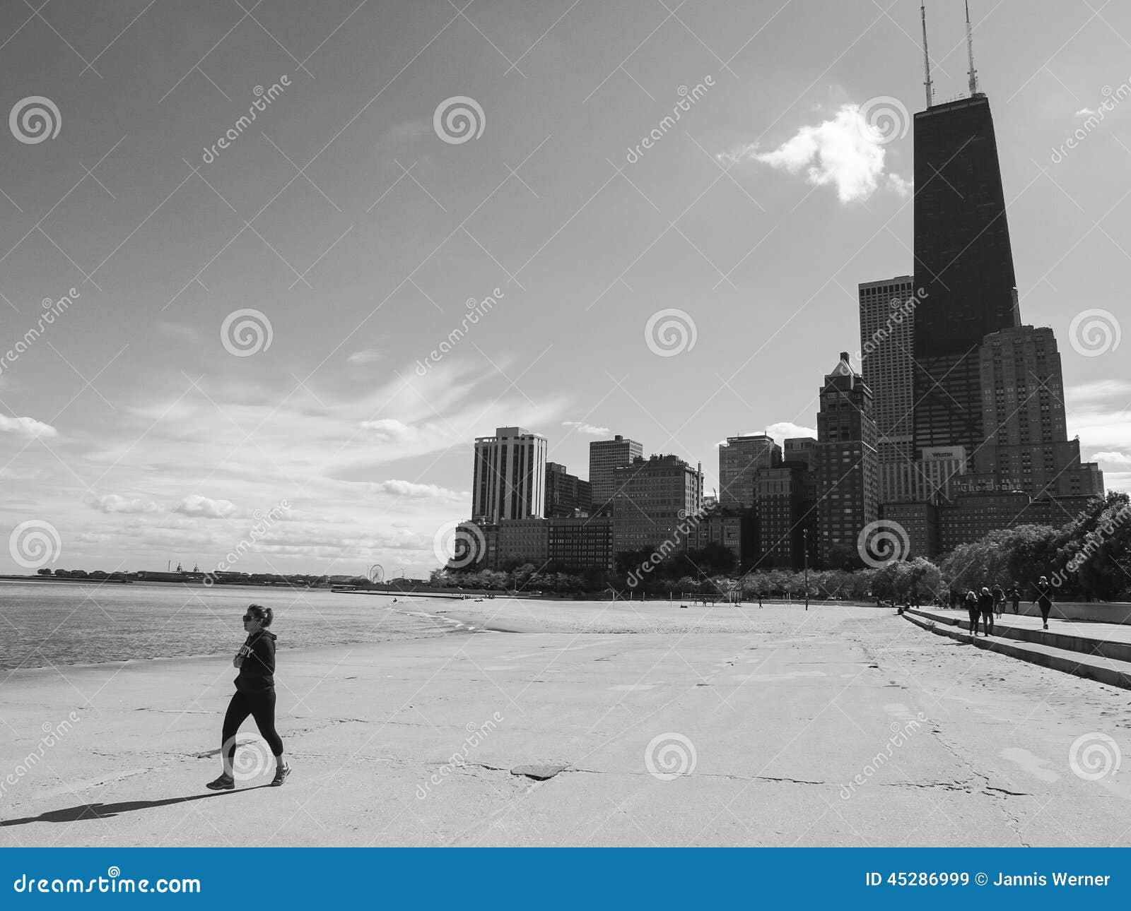 Strand Chicagos Gold Coast. CHICAGO, IL, USA - 5. OKTOBER 2014: Frau läuft entlang den Strand des Chicagos Gold Coast mit im Stadtzentrum gelegenen Wolkenkratzern im Hintergrund in Chicago, IL, USA am 5. Oktober 2014