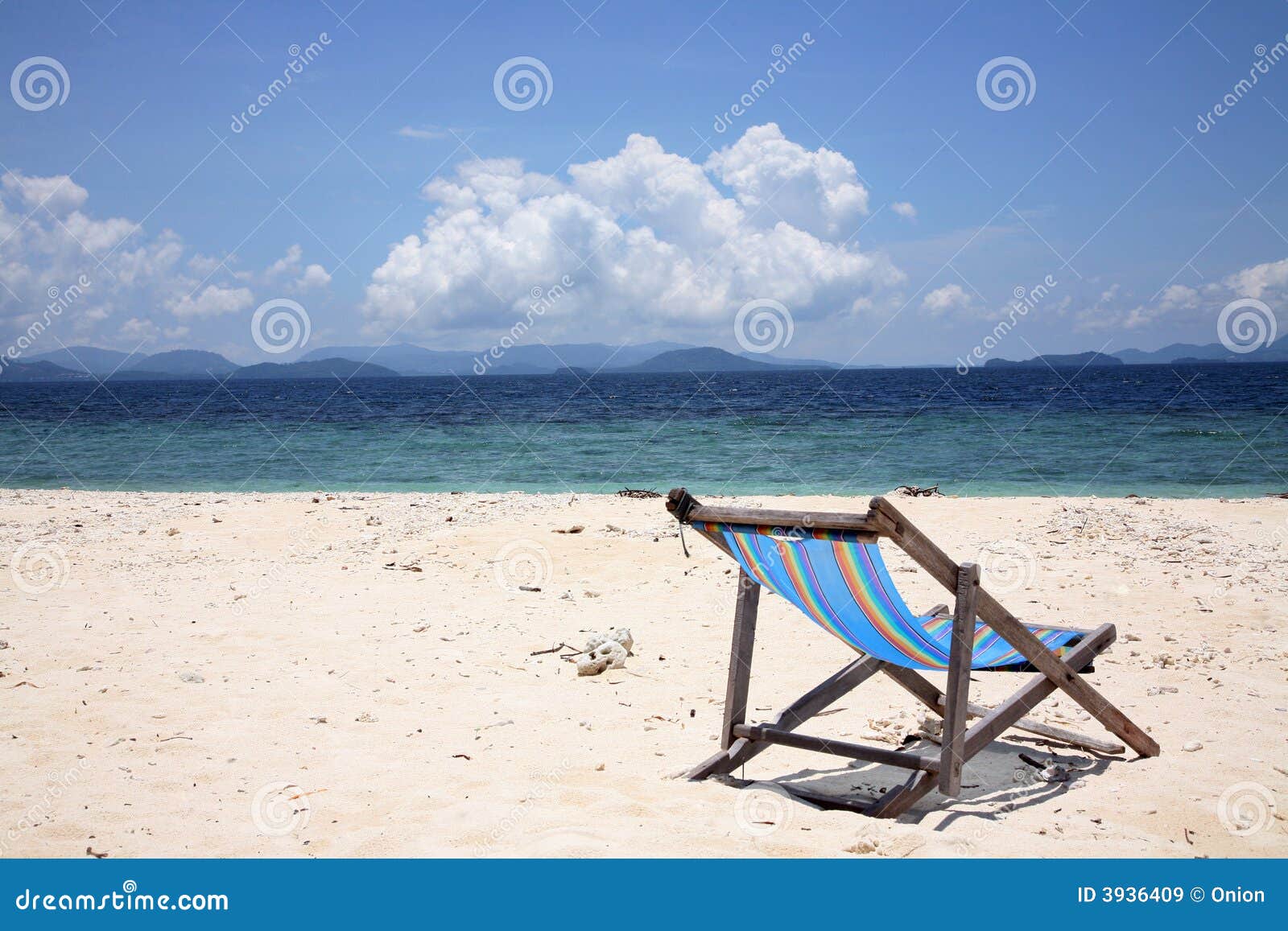 Einzelner Strandstuhl auf einem leeren Strand mit dem Meer im Hintergrund