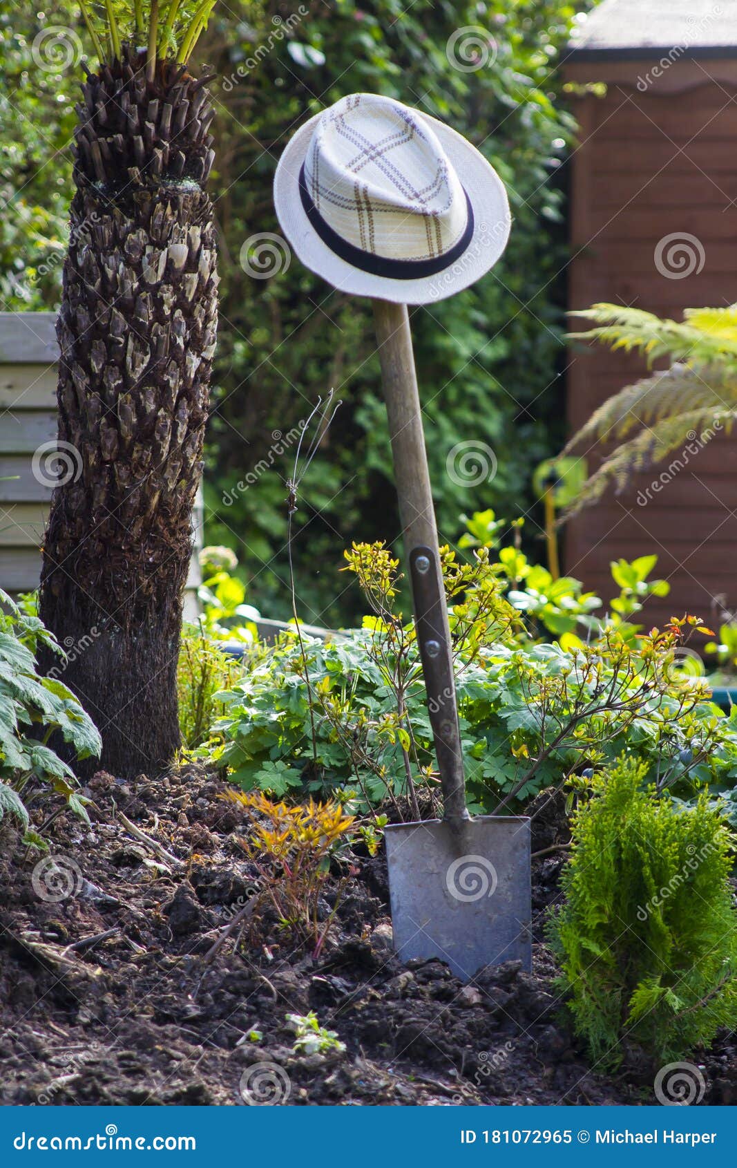 a straw hat hanging on a traditional garden spade