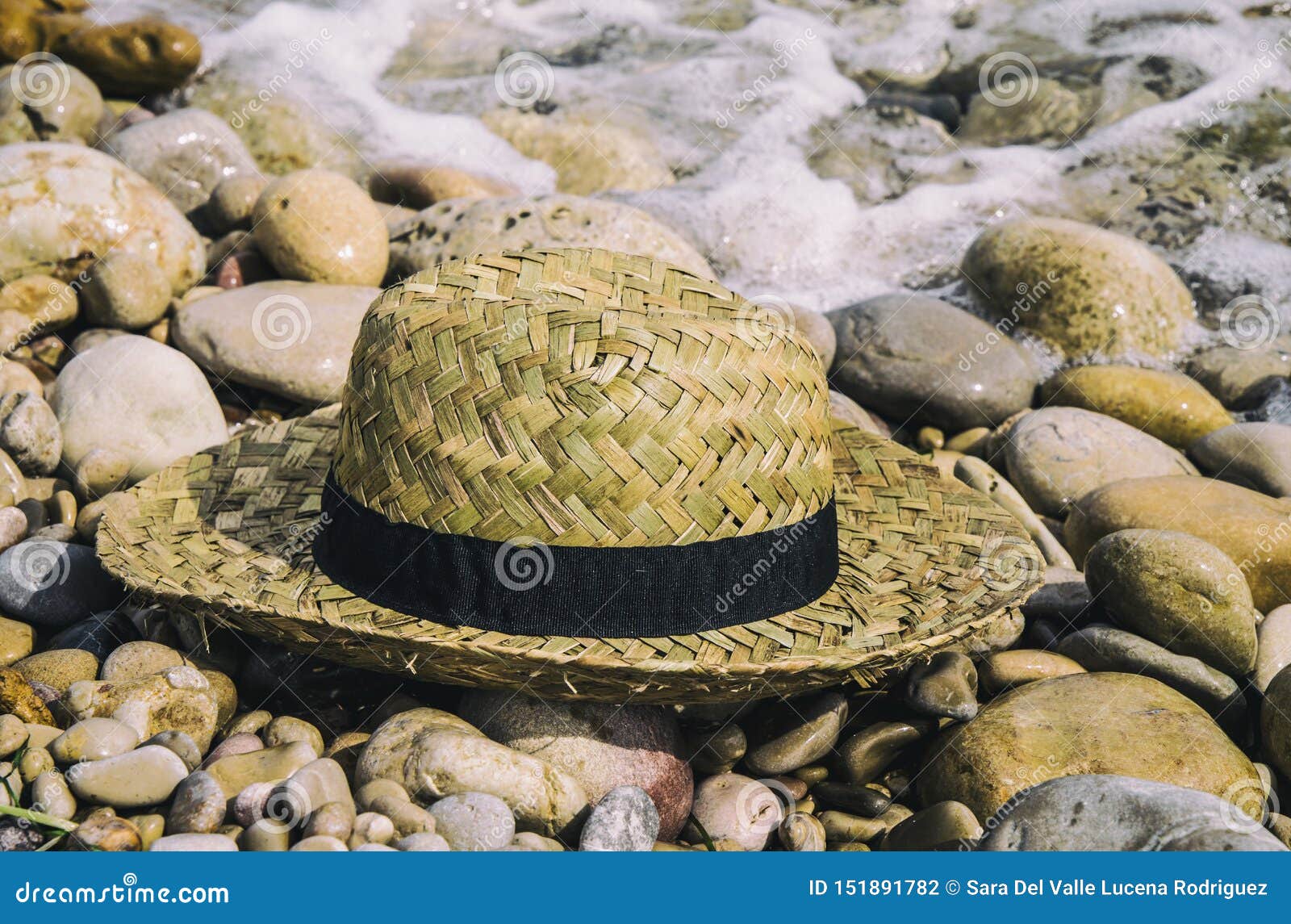 straw hat lying on top of beach stones