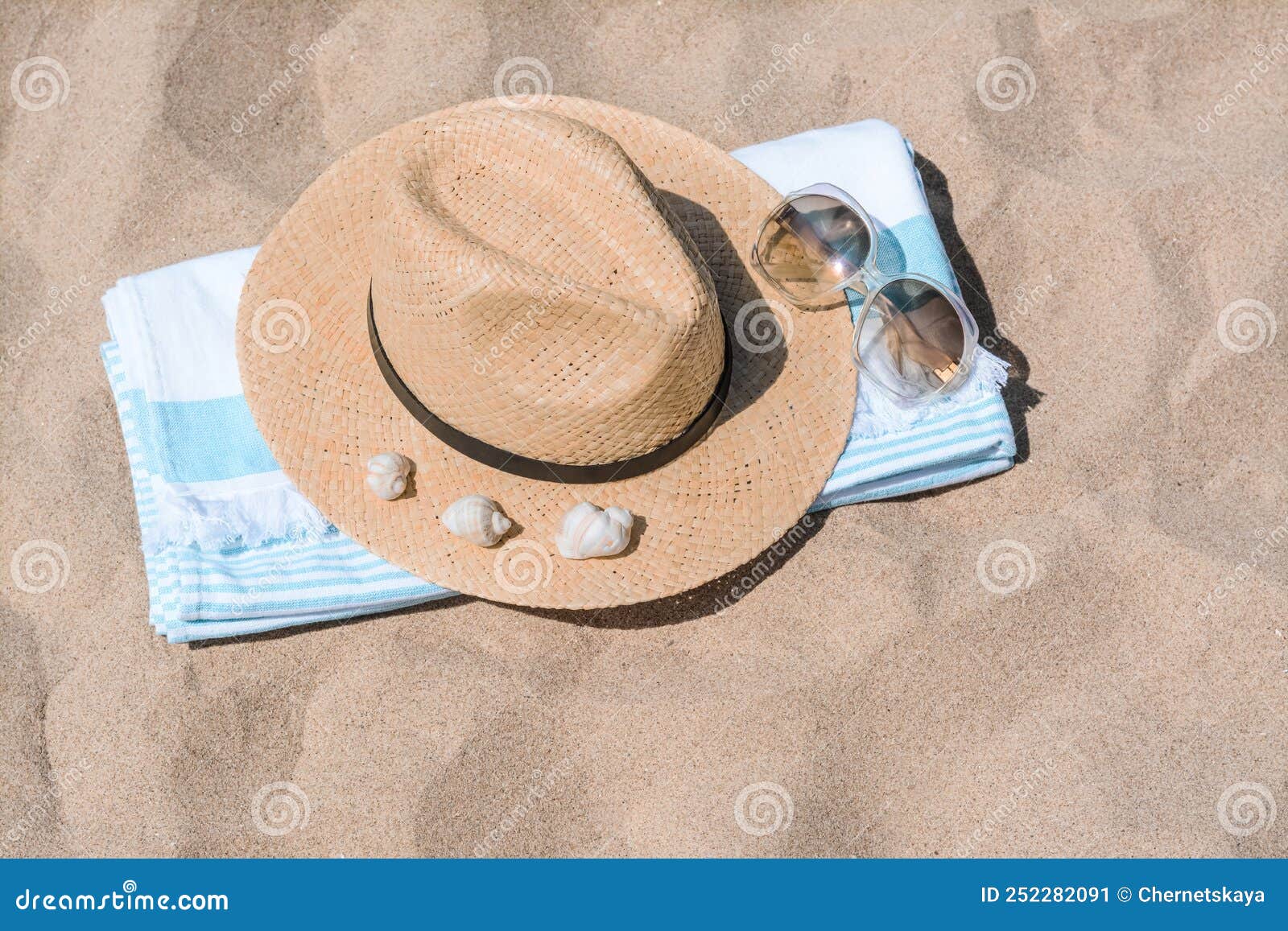 Straw Hat with Seashells, Sunglasses and Beach Towel on Sand Stock