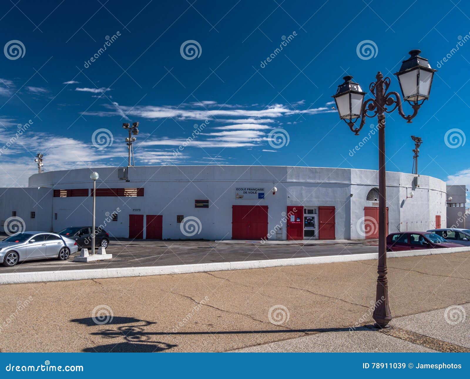 Straße in Saintes Maries de la Mer, Frankreich. Straßenlaternen auf Fahrbahn in Saintes Maries de la Mer, Frankreich am sonnigen Tag mit blauen Himmeln