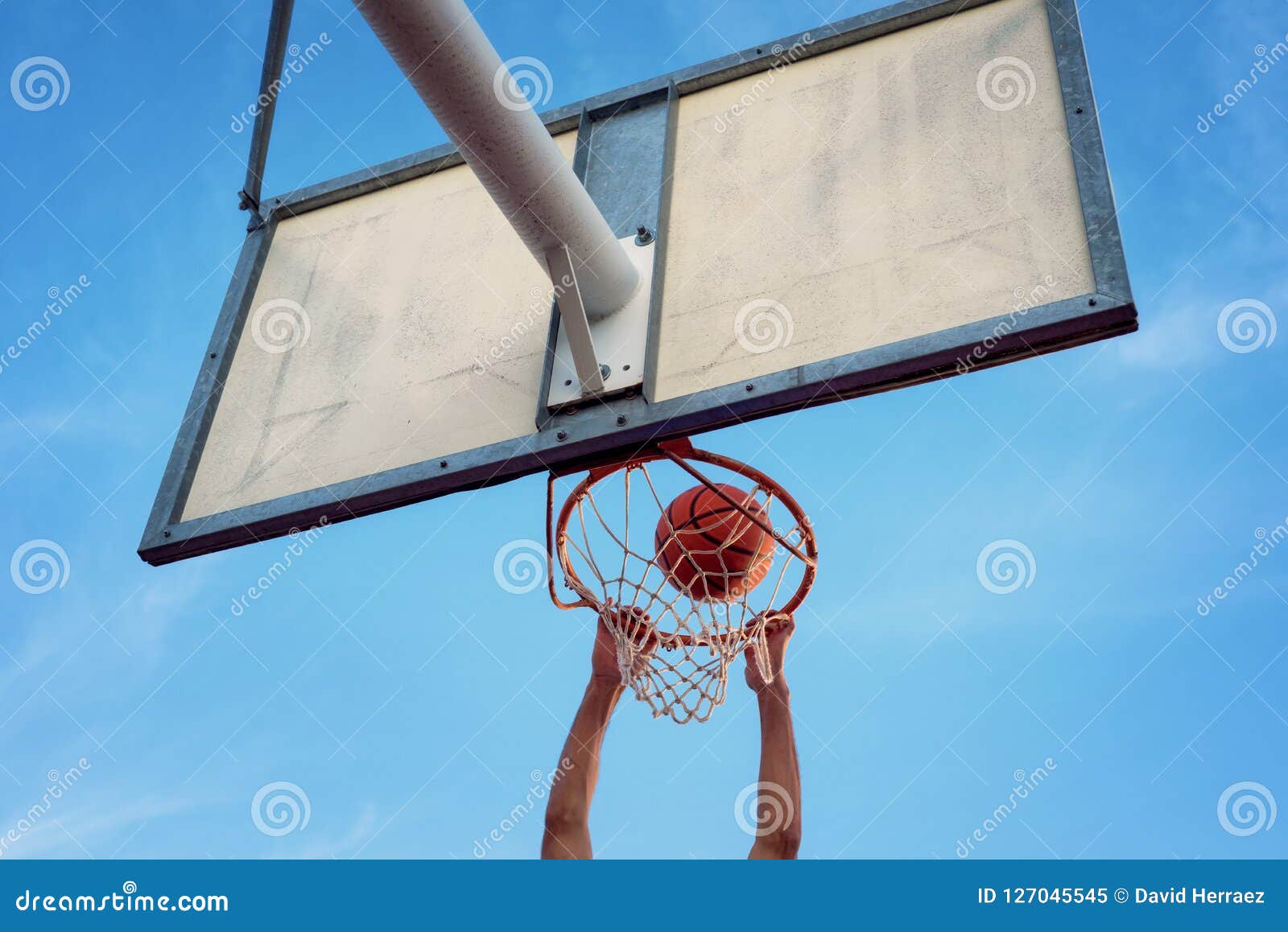 street basketball athlete performing slam dunk on the court