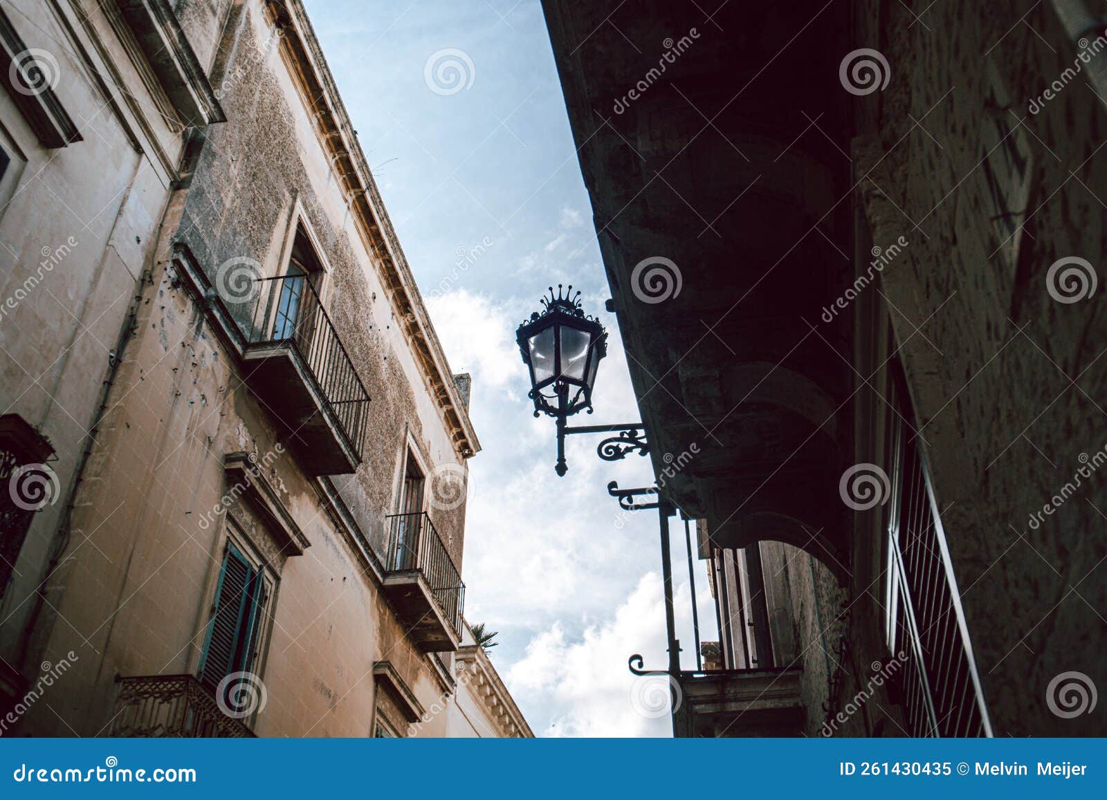 a street lamp with a crown on a wall in lecce with clear blue skies, italy