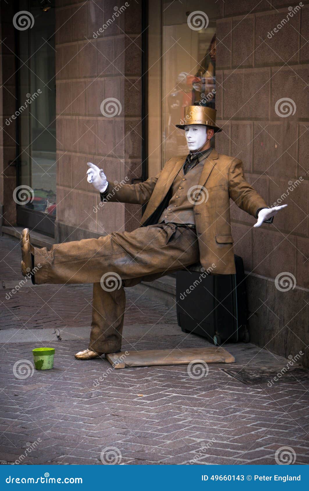 A Street Performer as a Golden Statue. A street performer as a statue in Italy dressed in gold with white hands and face.