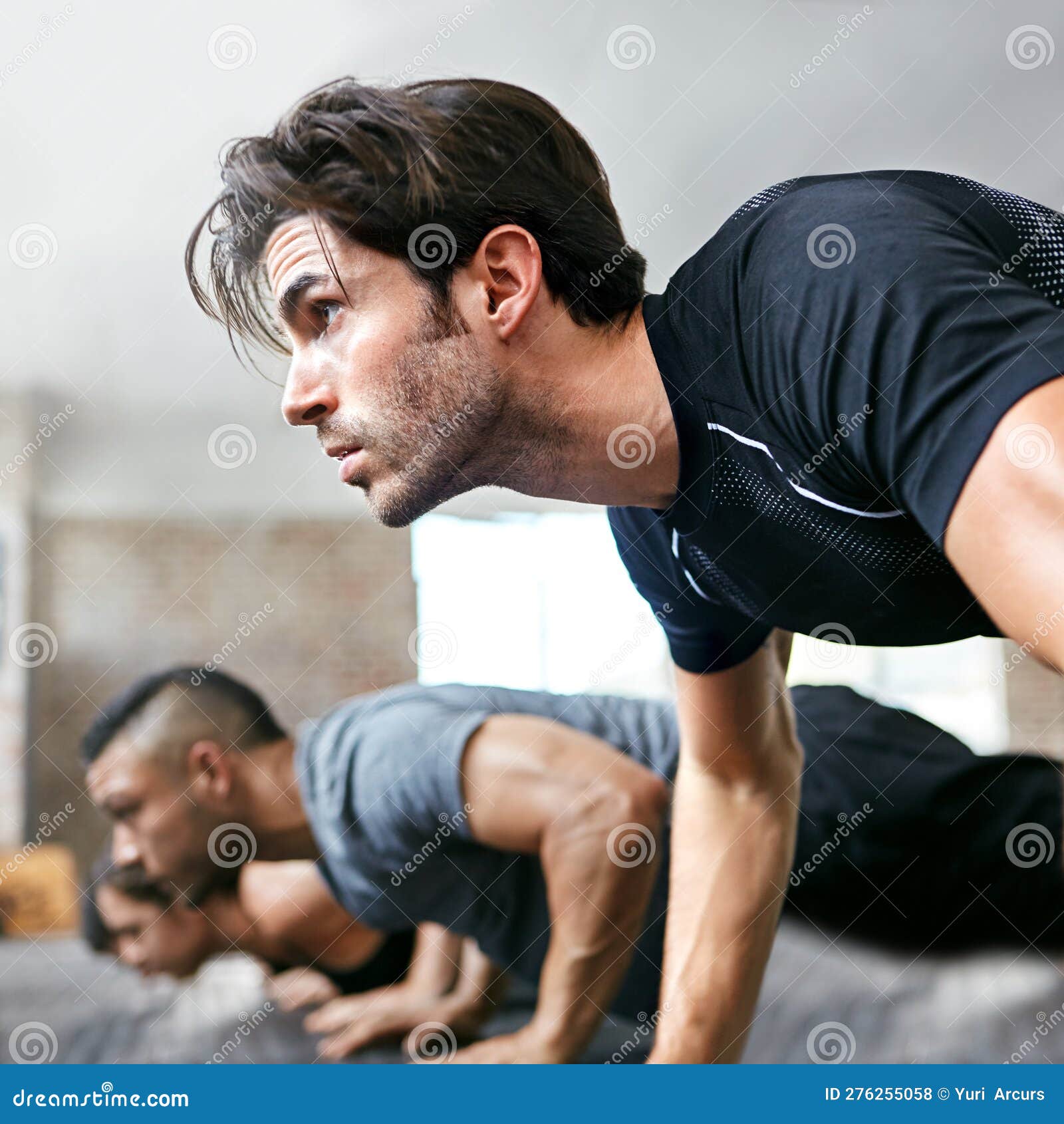 Strength of Body and Mind. a Group of People Doing Push Ups in a Gym