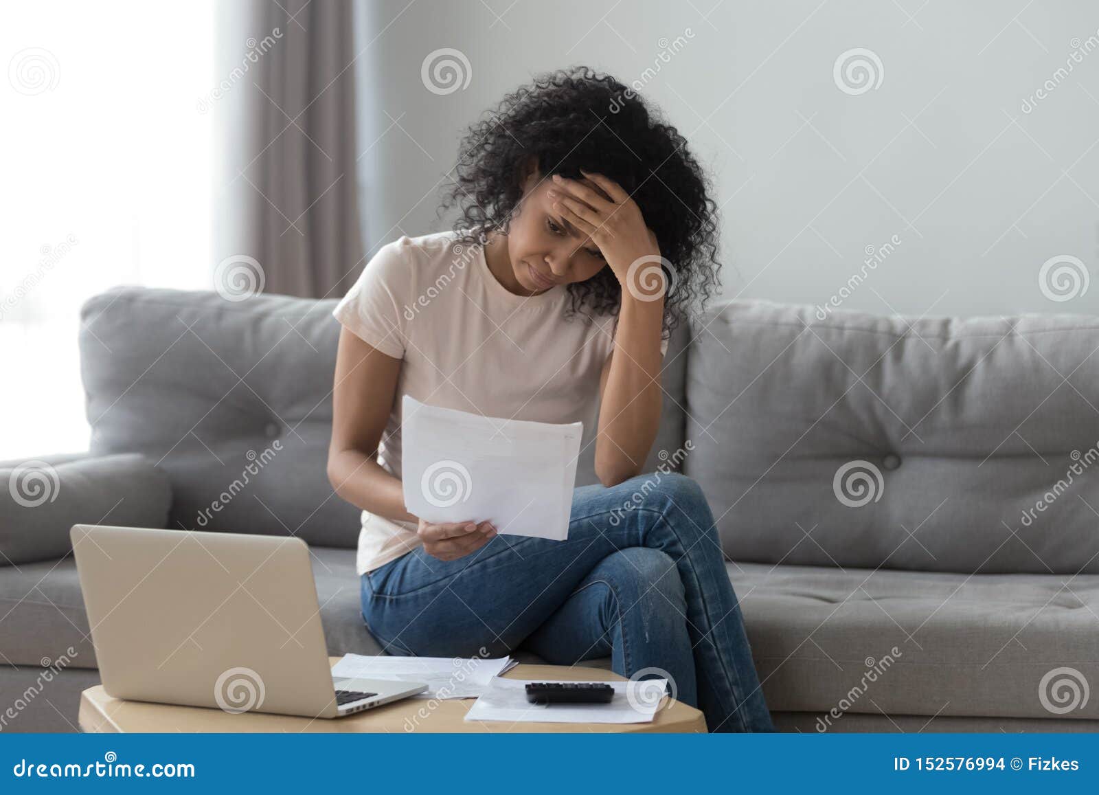 stressed african woman holding bills worried about bankruptcy bank debt