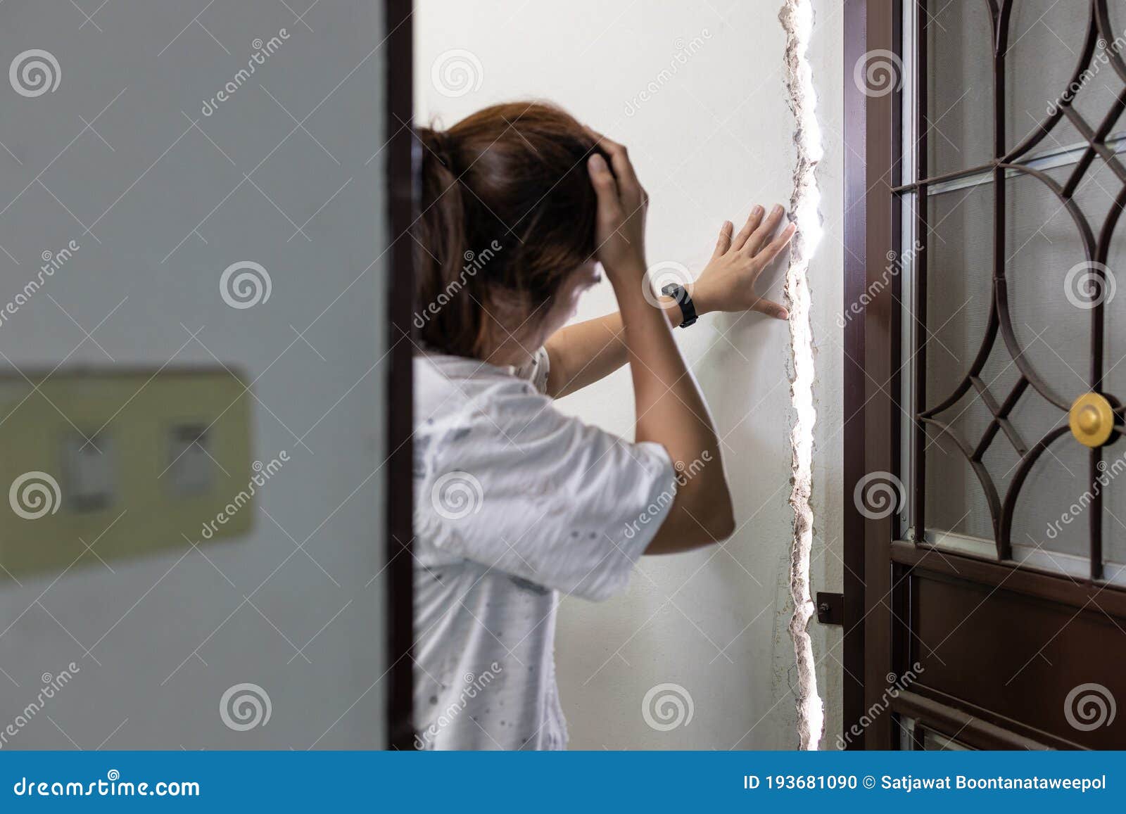 stressed asian female people is standing at the cracks,rift of wall in her house feeling disappointed,regretted,repair or