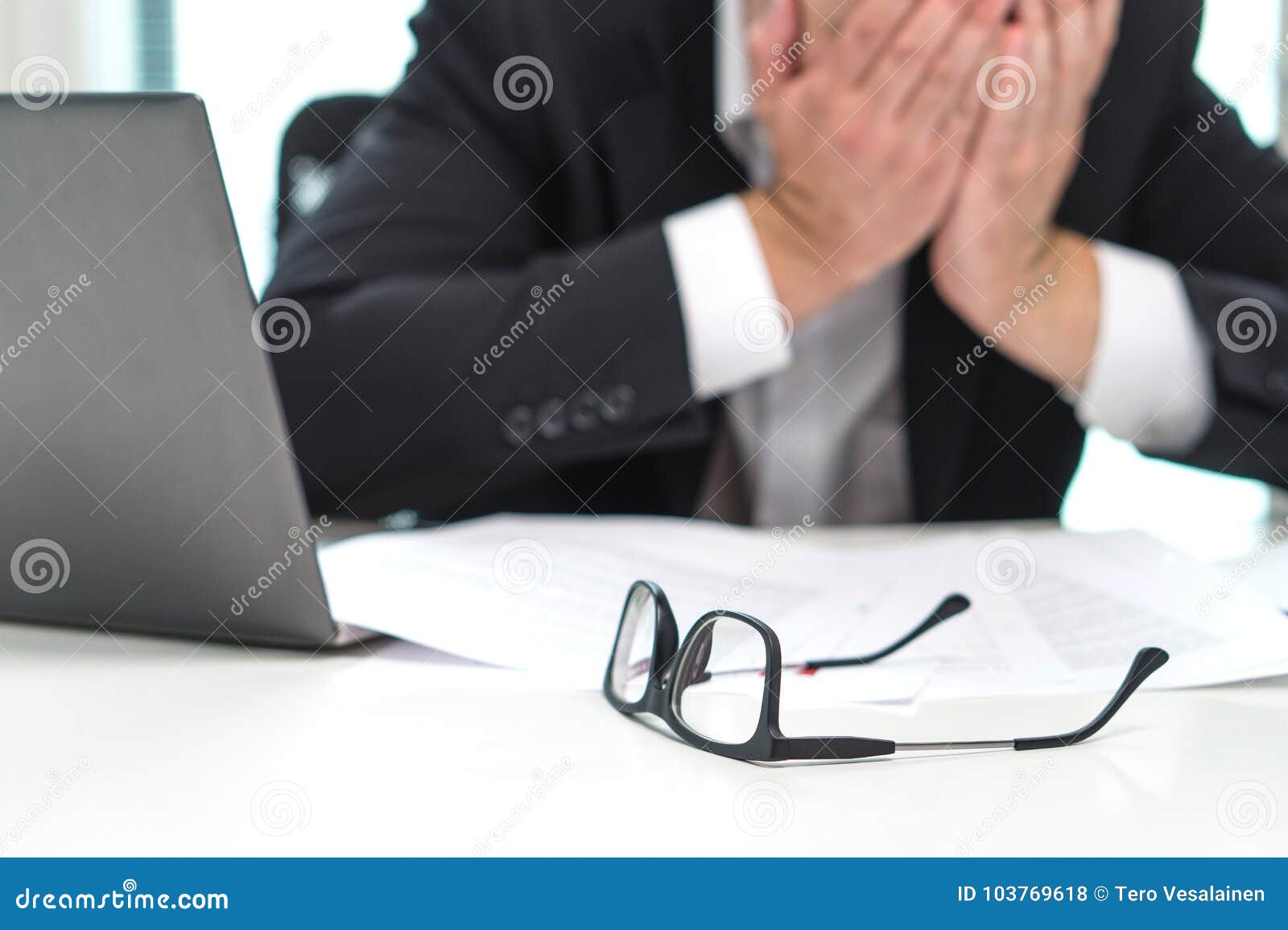 stressed business man covering face with hands in office.