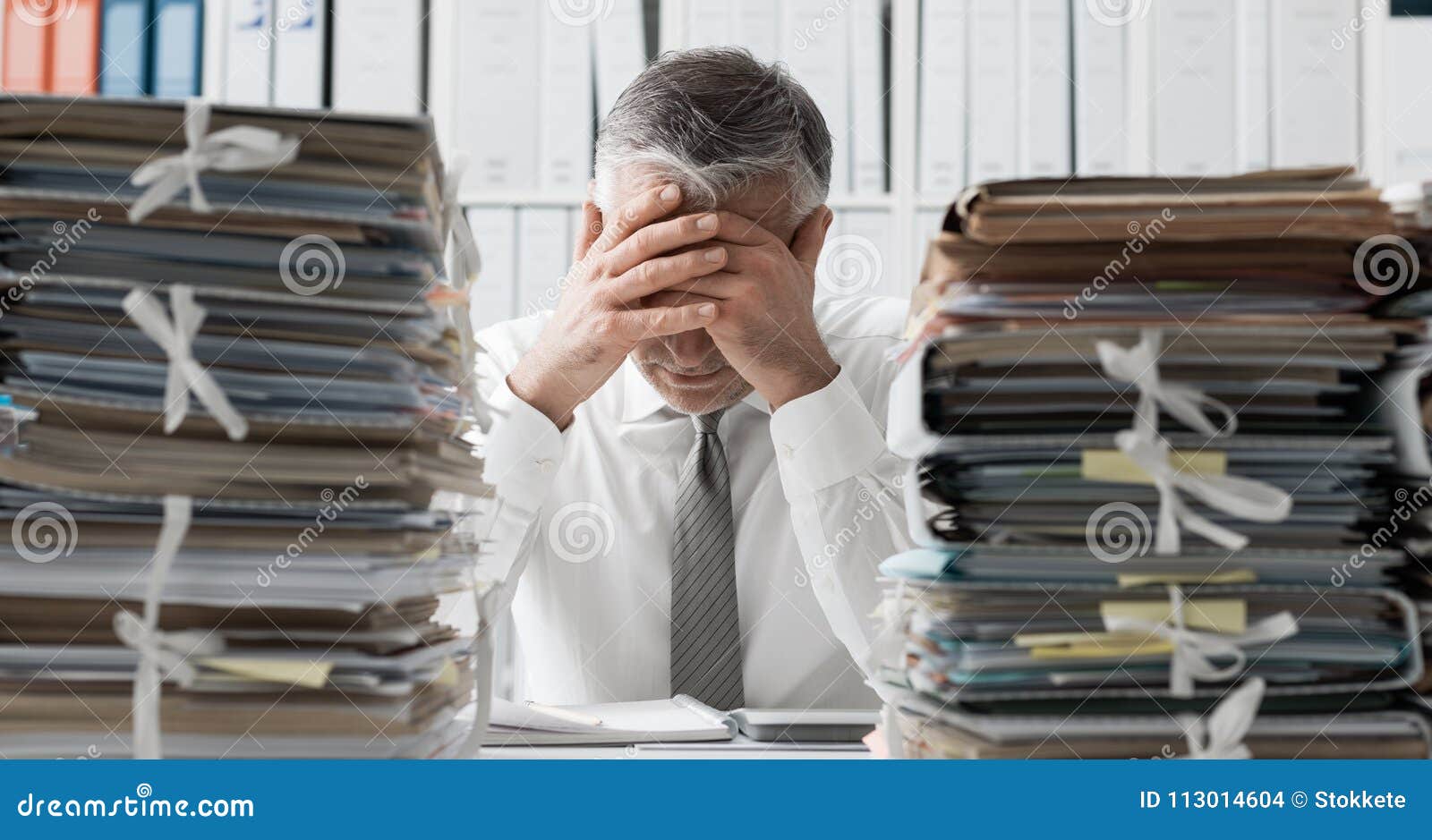 Stressed Business Executive And Piles Of Paperwork Stock Photo