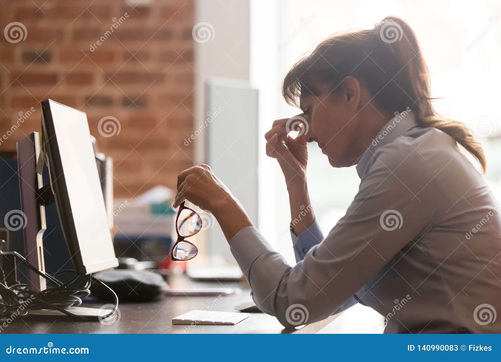 stressed overworked middle aged businesswoman office worker taking off glasses