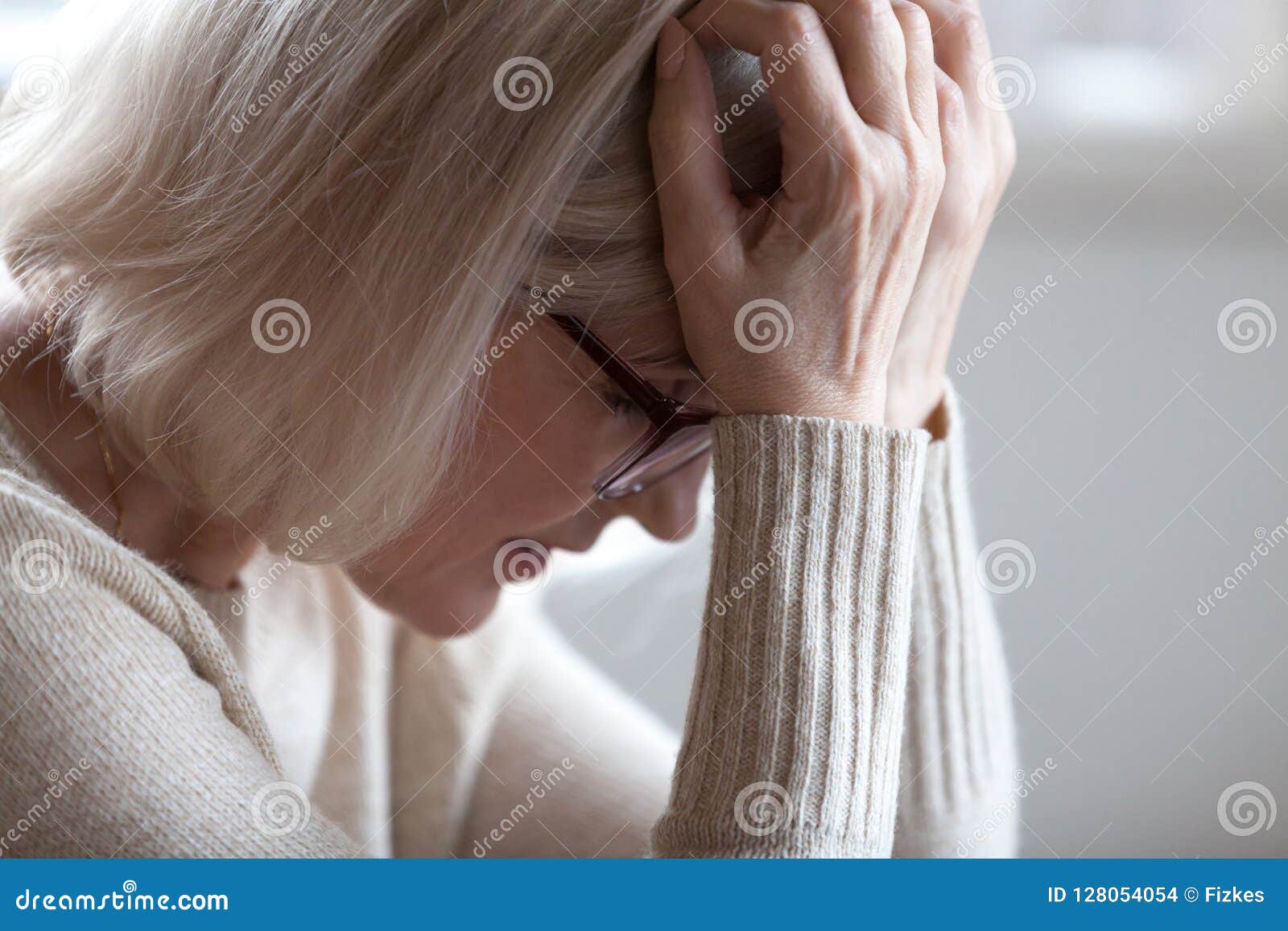 sad tired senior woman holding head in hands feeling headache