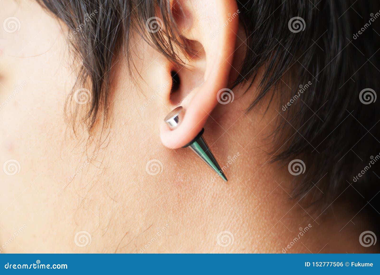 stretching ears for larger diameter tunnels,piercer hand inserts the piercing in the ear