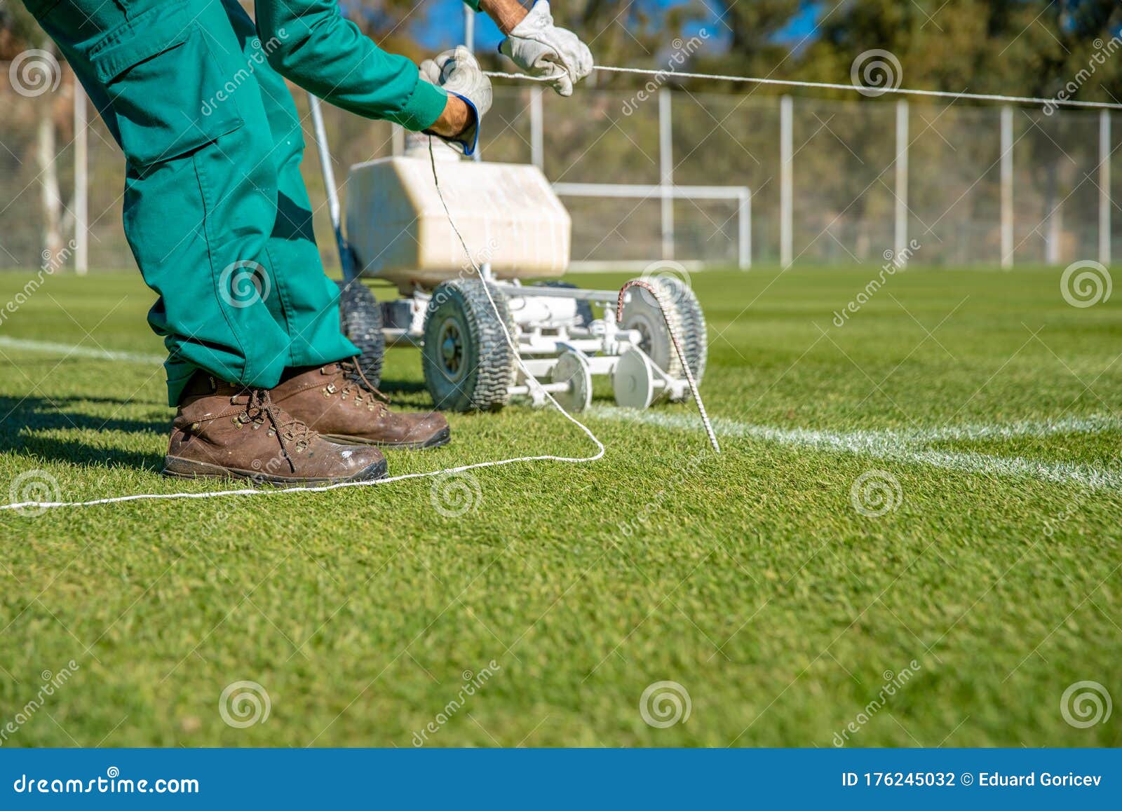 Stretching a Rope for Lining a Football Field Using White Paint on the